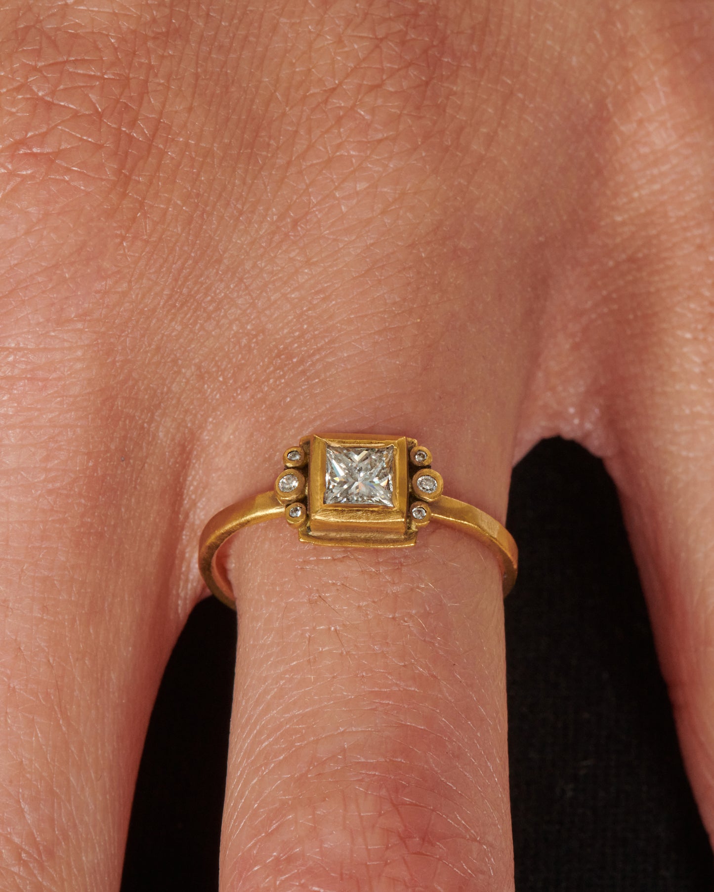 A square diamond in a matching bezel with three round diamonds on either side.