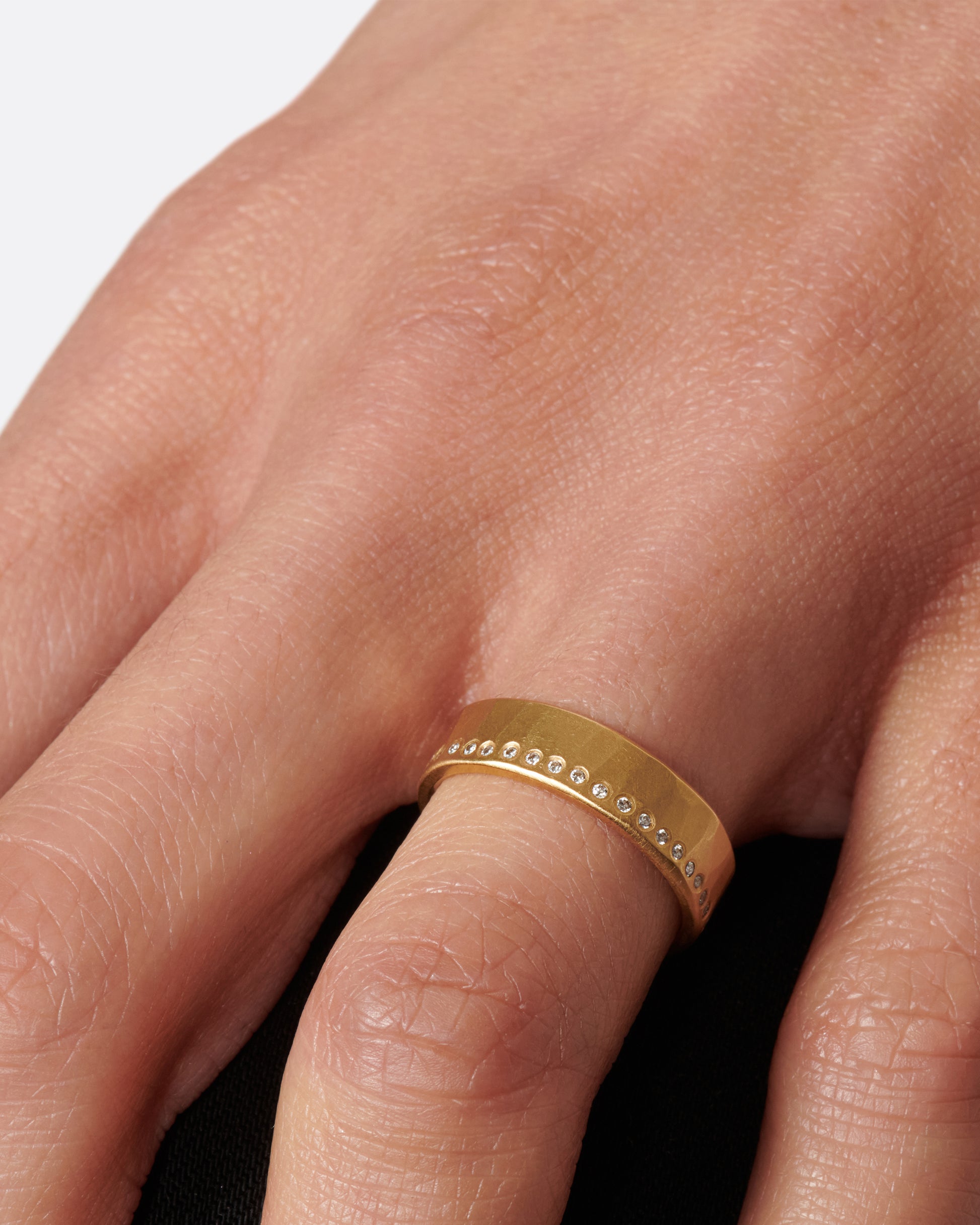 A hammered, matte gold band with a line of round diamonds all the way around.