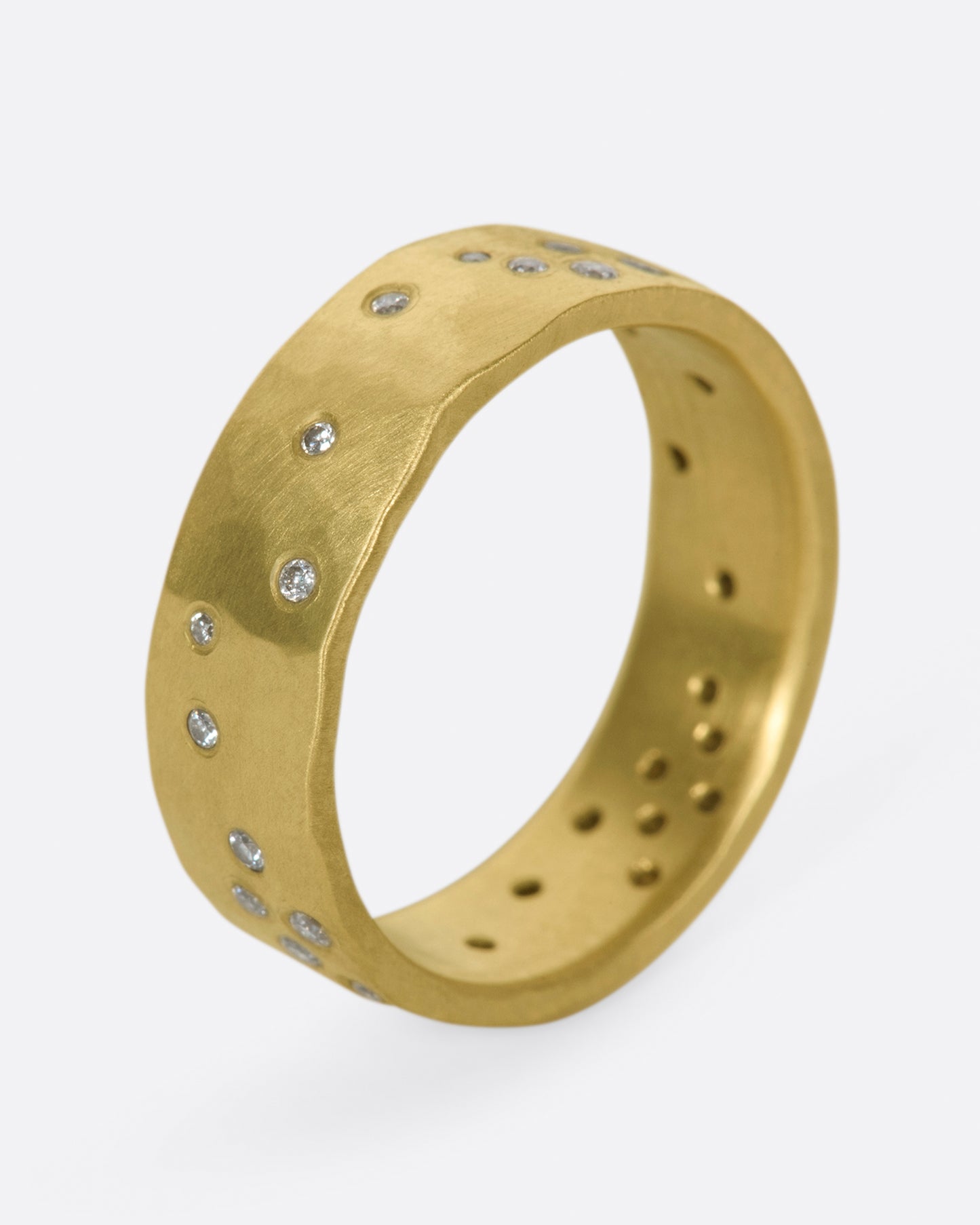 A constellation of thirty sparkling white diamonds set on a wide, hammered, matte gold band.