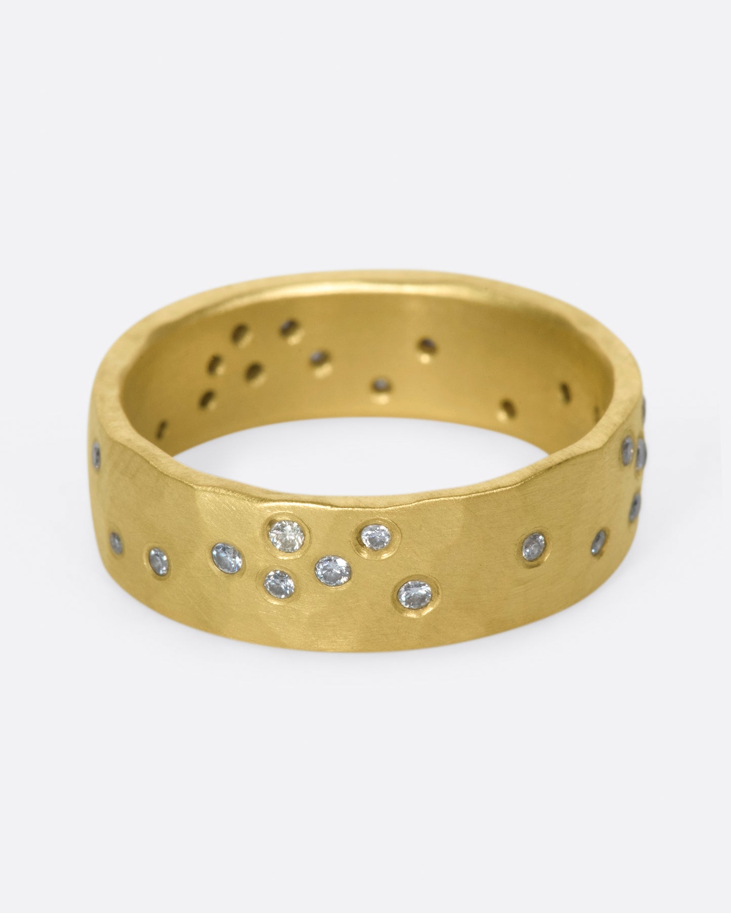 A constellation of thirty sparkling white diamonds set on a wide, hammered, matte gold band.