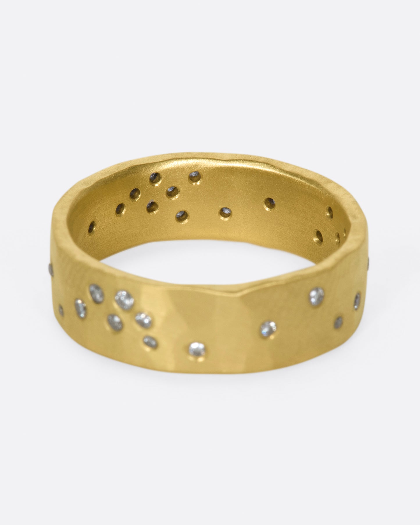 A constellation of thirty sparkling white diamonds set on a wide, hammered, matte gold band.