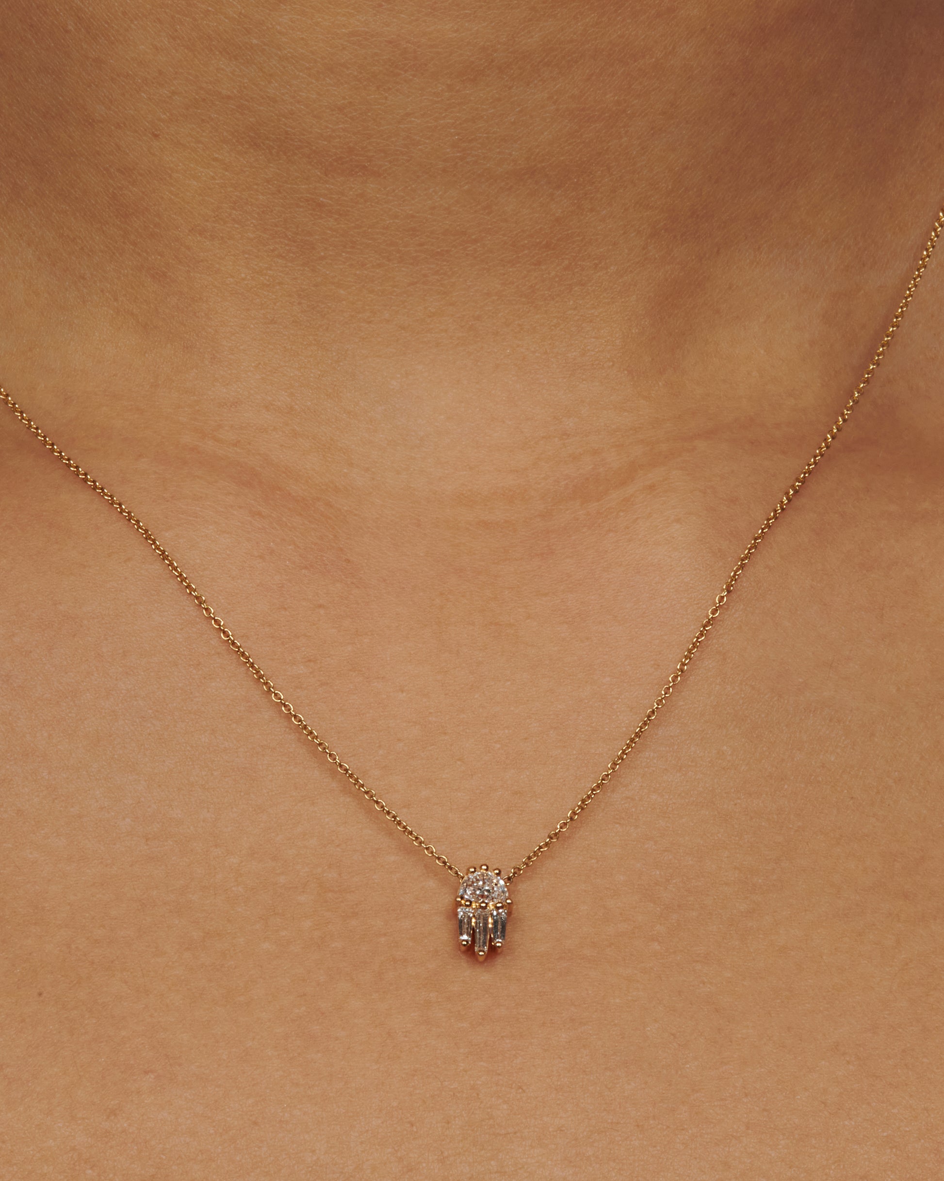 A diamond pendant necklace with a half moon and three tapered baguette diamonds.