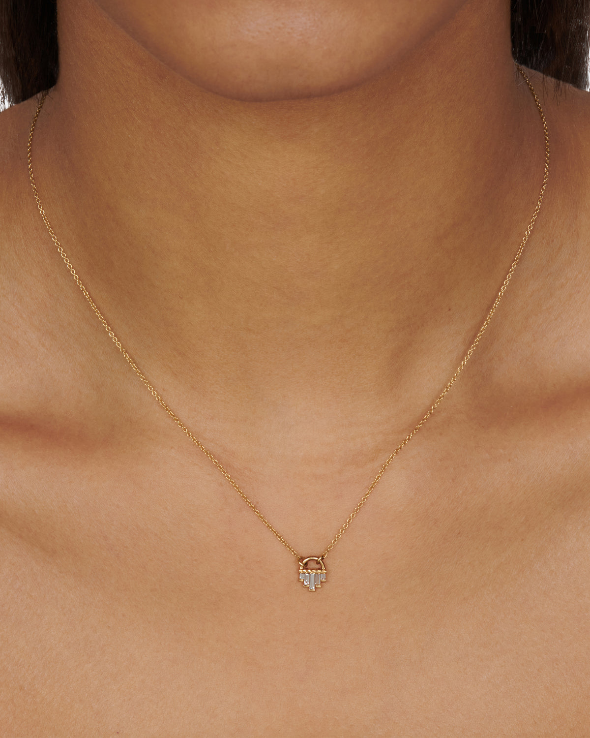 A curved gold pendant necklace with five diamond baguettes.