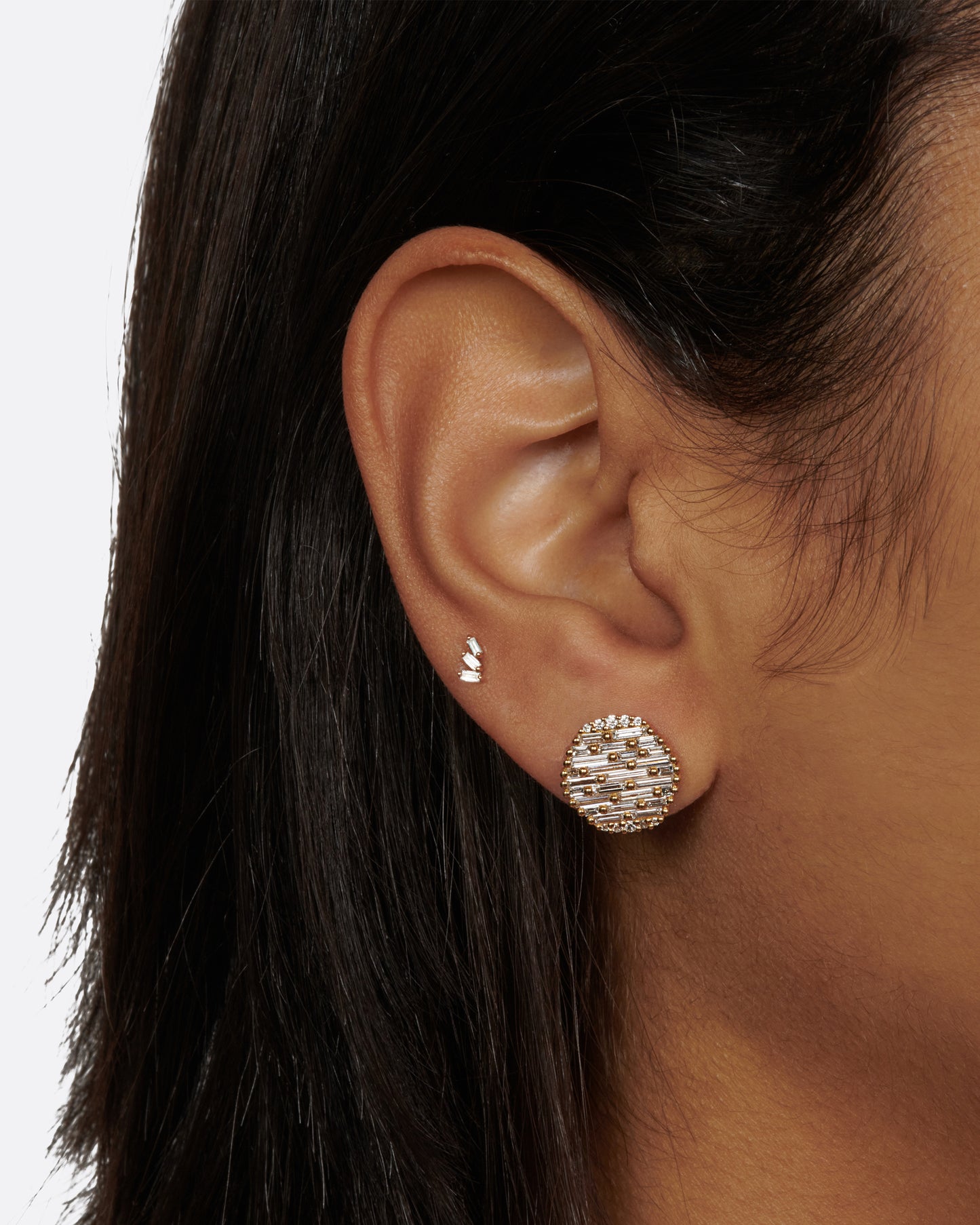 A pair of round, slightly concave stud earrings covered in baguette diamonds.