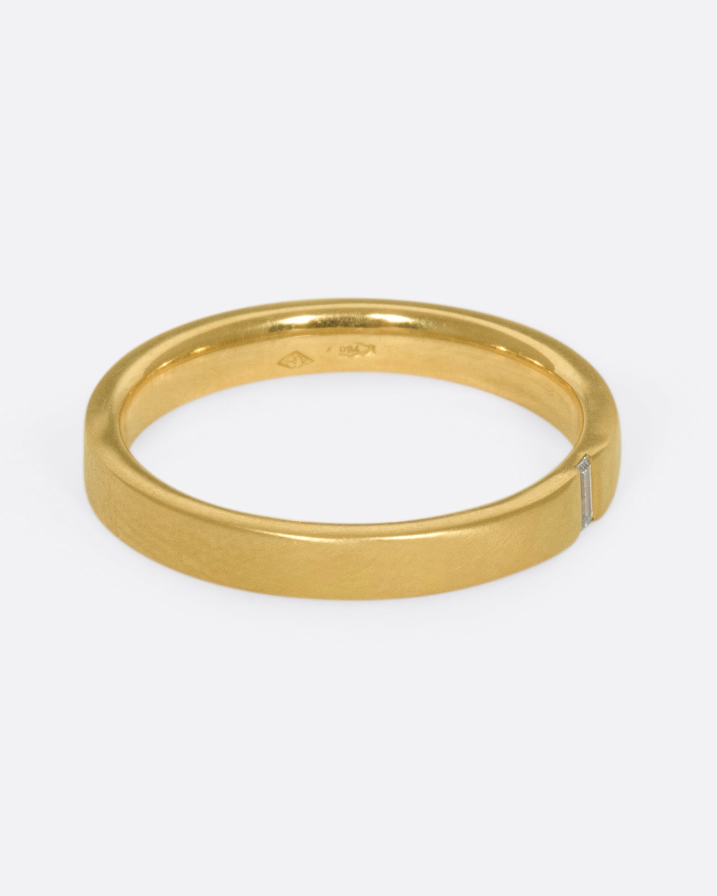 A matte gold band cast in a simple silhouette, featuring one needle baguette-cut diamond for that extra flare.