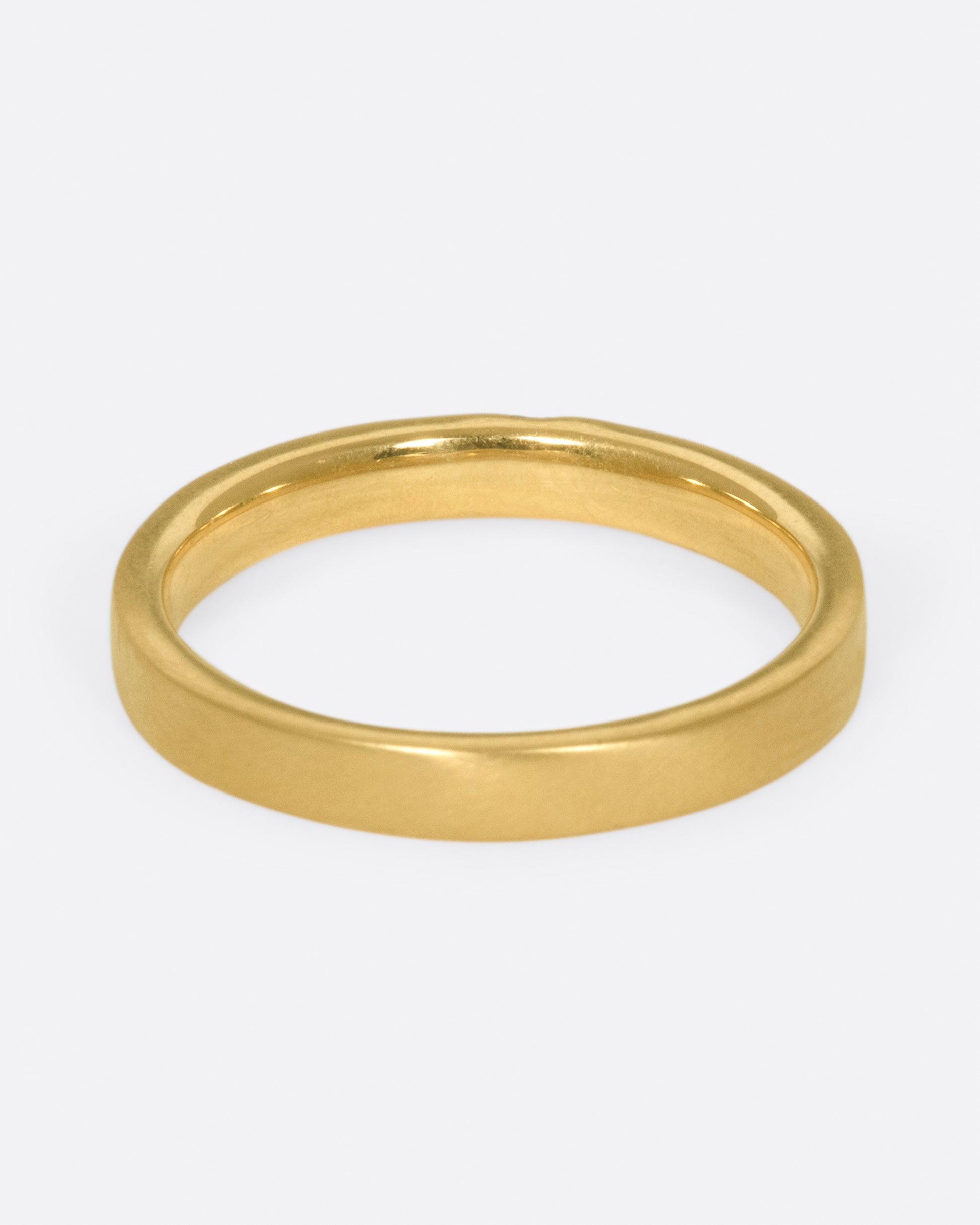 A matte gold band cast in a simple silhouette, featuring one needle baguette-cut diamond for that extra flare.