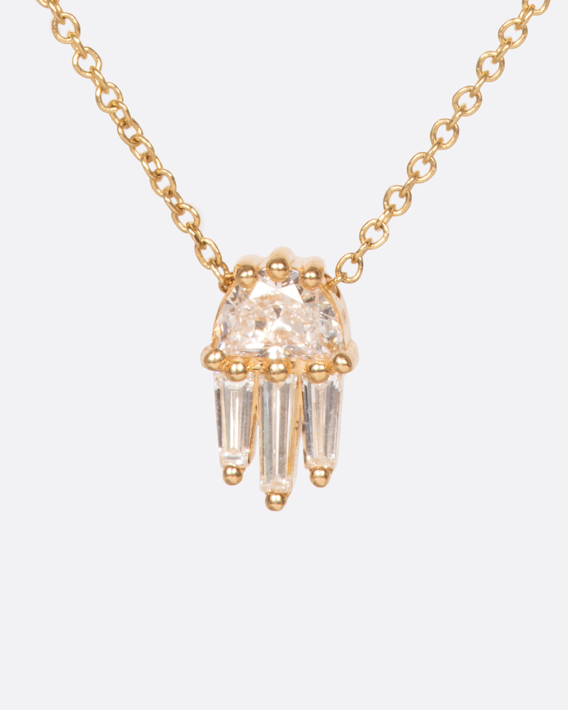 A diamond pendant necklace with a half moon and three tapered baguette diamonds.