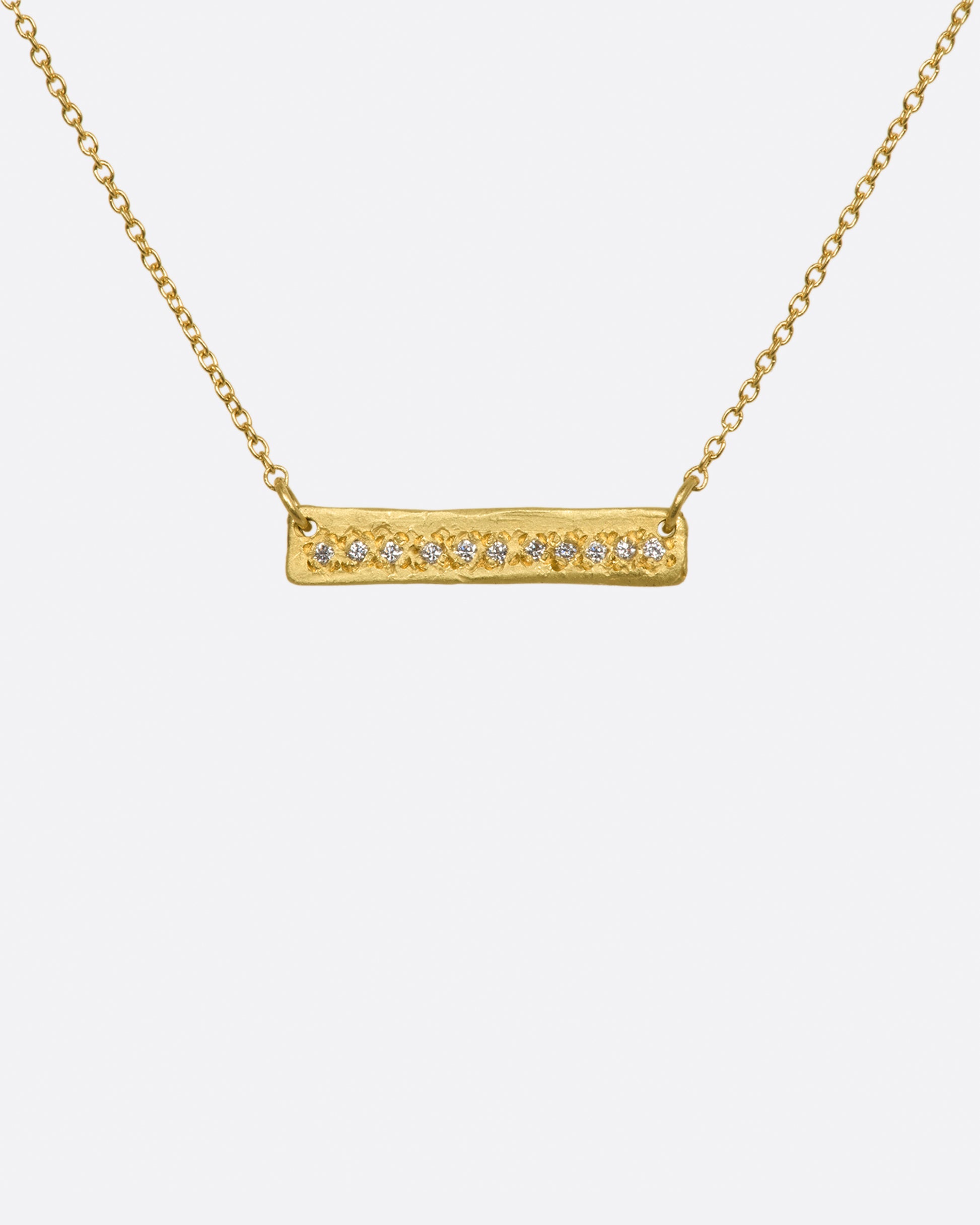 A yellow gold bar necklace with a single row of white diamonds. View from the front.