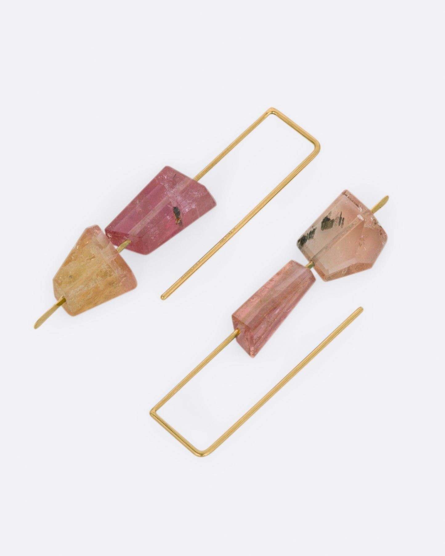 Yellow gold rectangular hook earrings with two pink tourmalines on each. View laying flat.