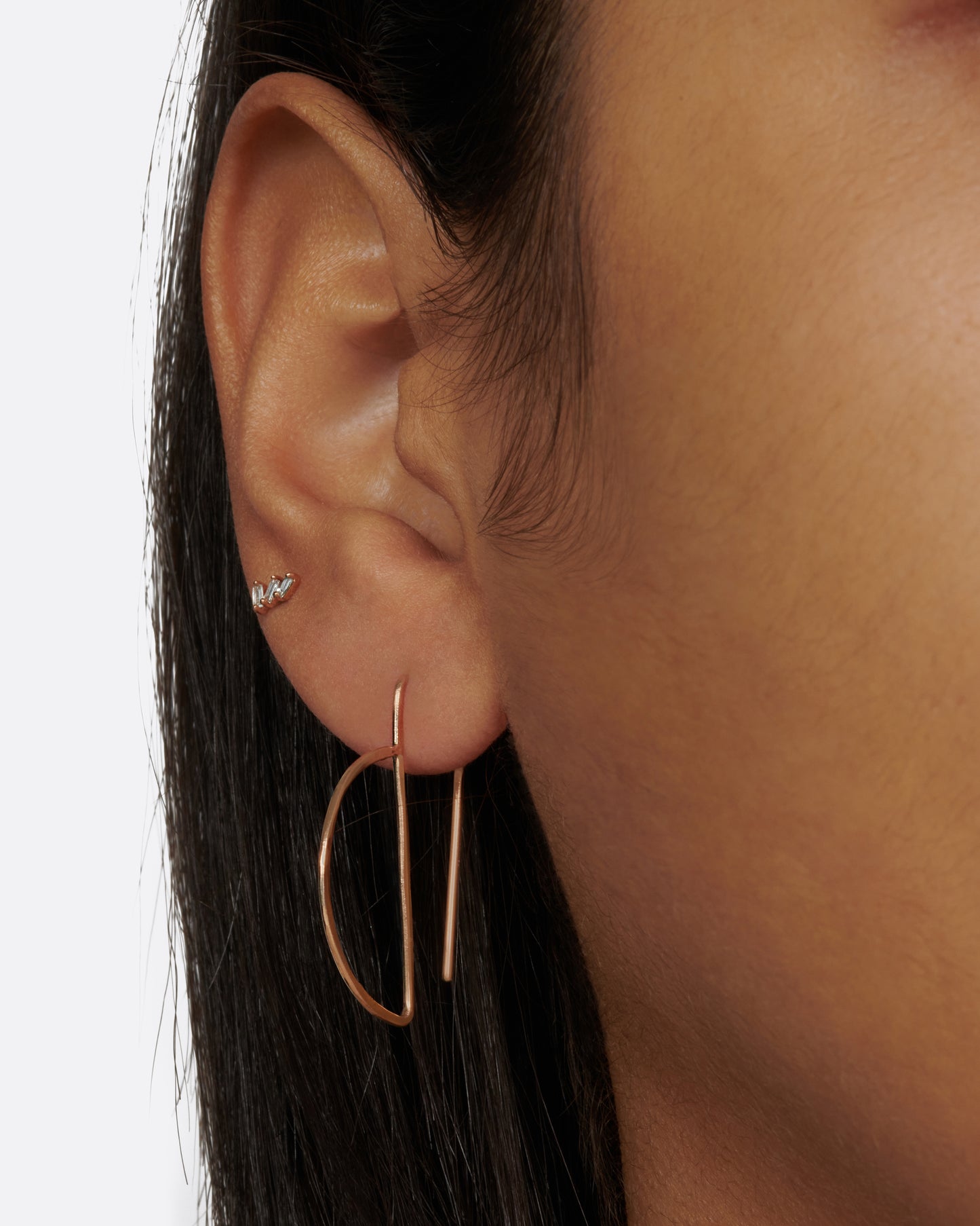 These hammered gold earrings thread through the ear so that the straight bar sits comfortably behind your lobe and the curve shows in front.