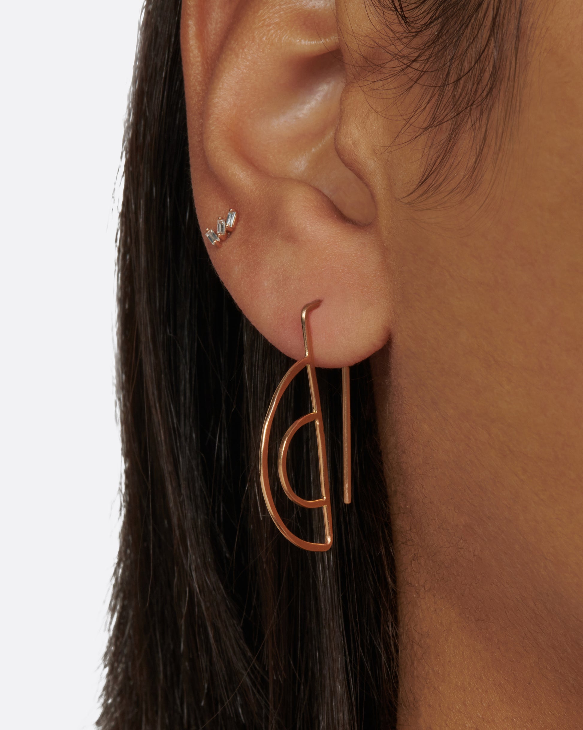 These double semi-circle earrings face forward and the long straight wires hang behind the earlobe; framing the face.