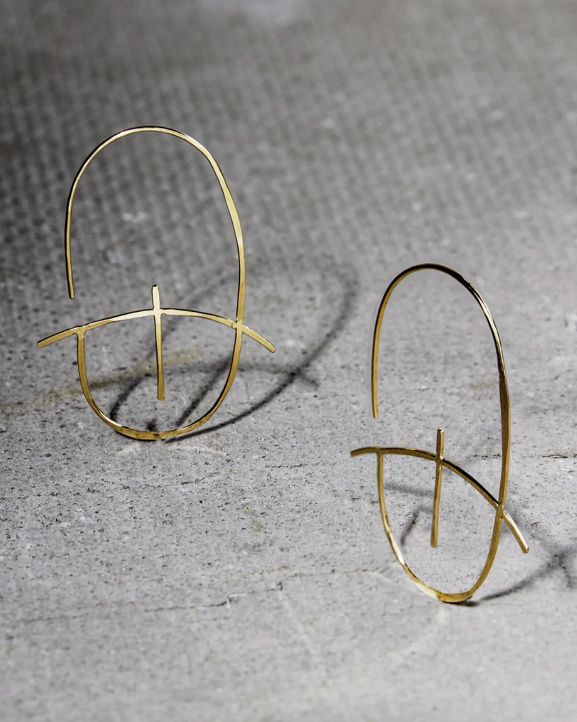 A geometric earring made of thin yellow gold with a hammered finish