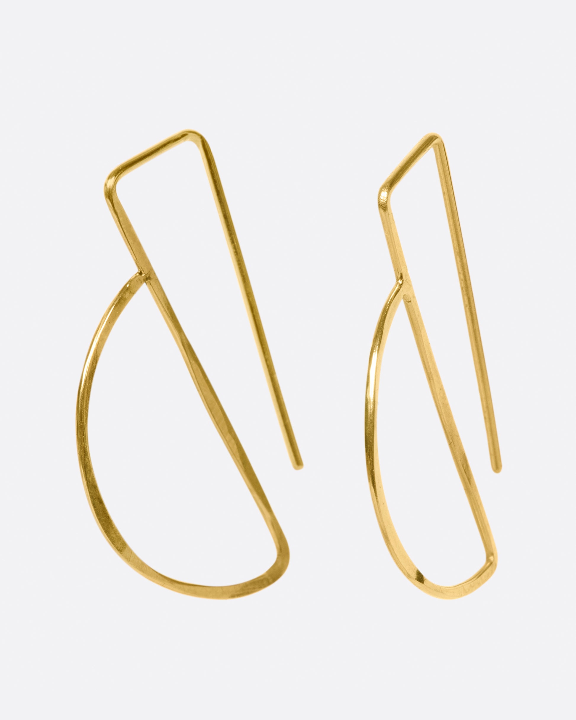 These hammered gold earrings thread through the ear so that the straight bar sits comfortably behind your lobe and the curve shows in front.