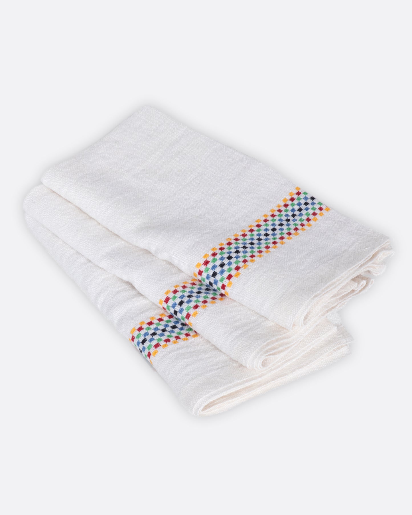 A white linen napkin with rainbow checkered embroidered stripes