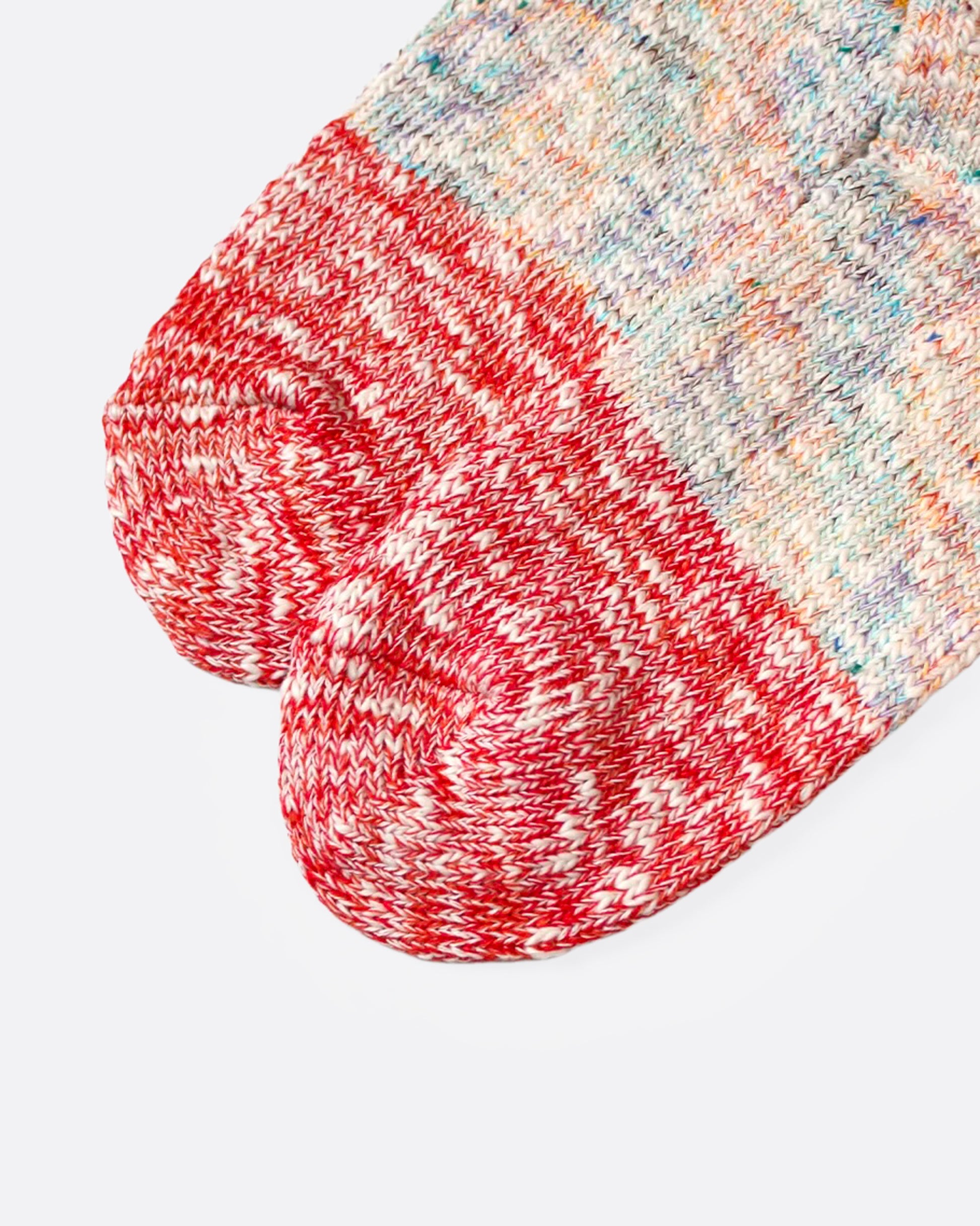A close up of a pair of multicolored marl socks with dual-toned heels, shown from the side.