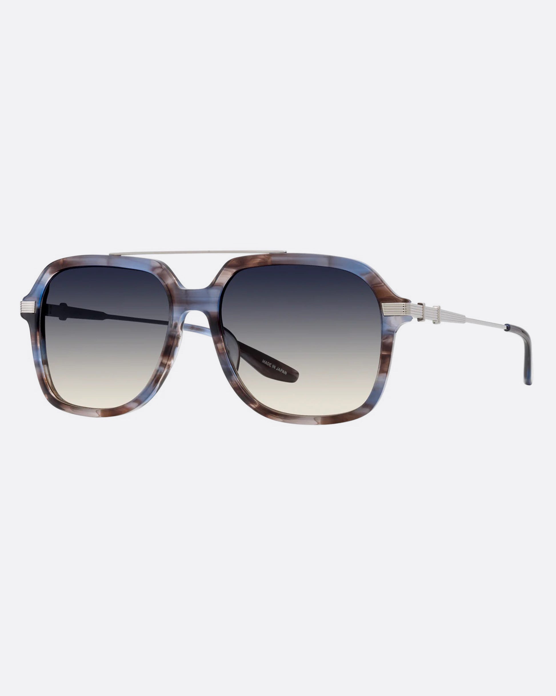 A pair of navigator sunglasses  with pearly blue and silver structured frames and gray gradient lenses. Shown diagonally from the front.
