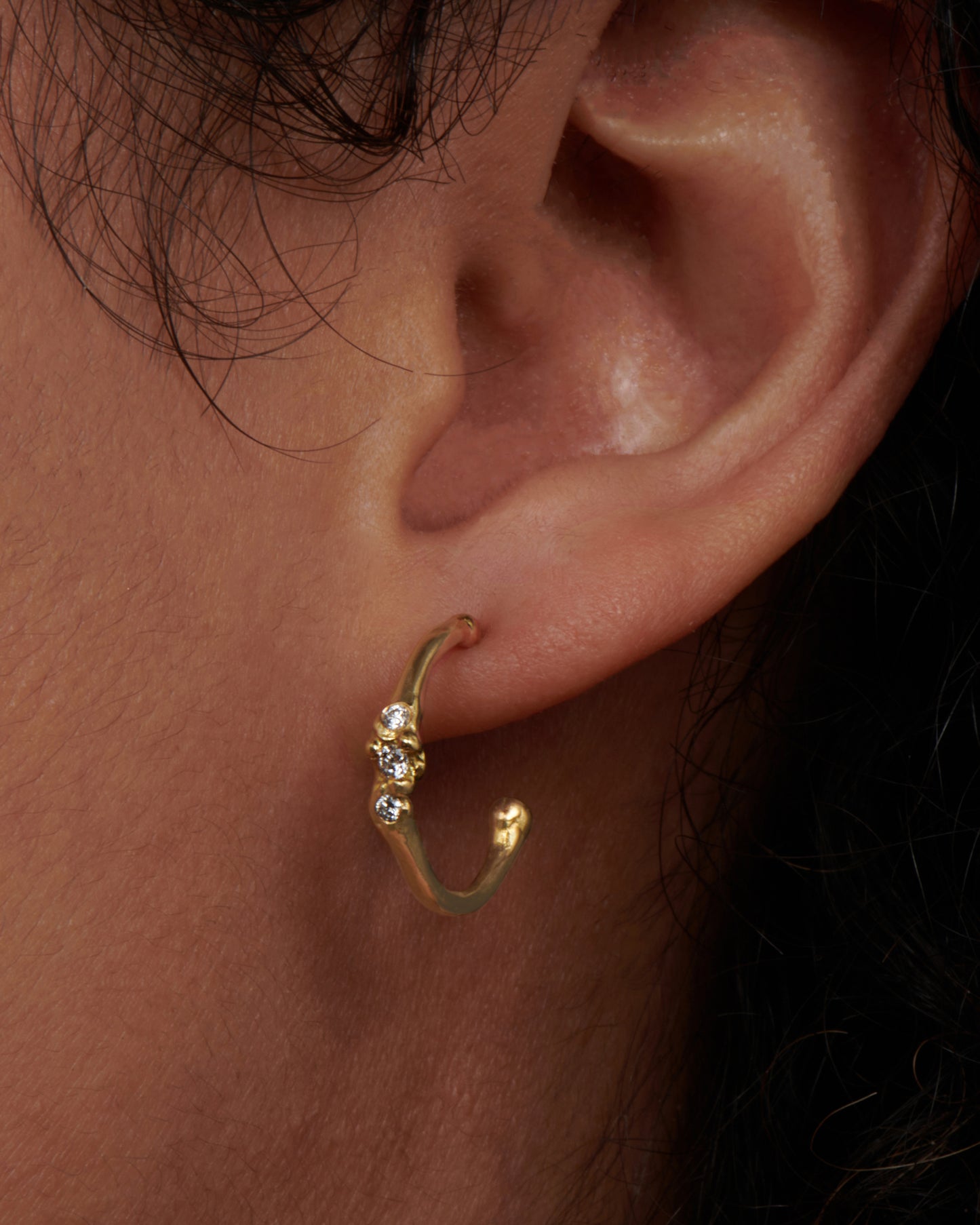 18k gold stud hoops with three diamonds set across the front. View on an ear.