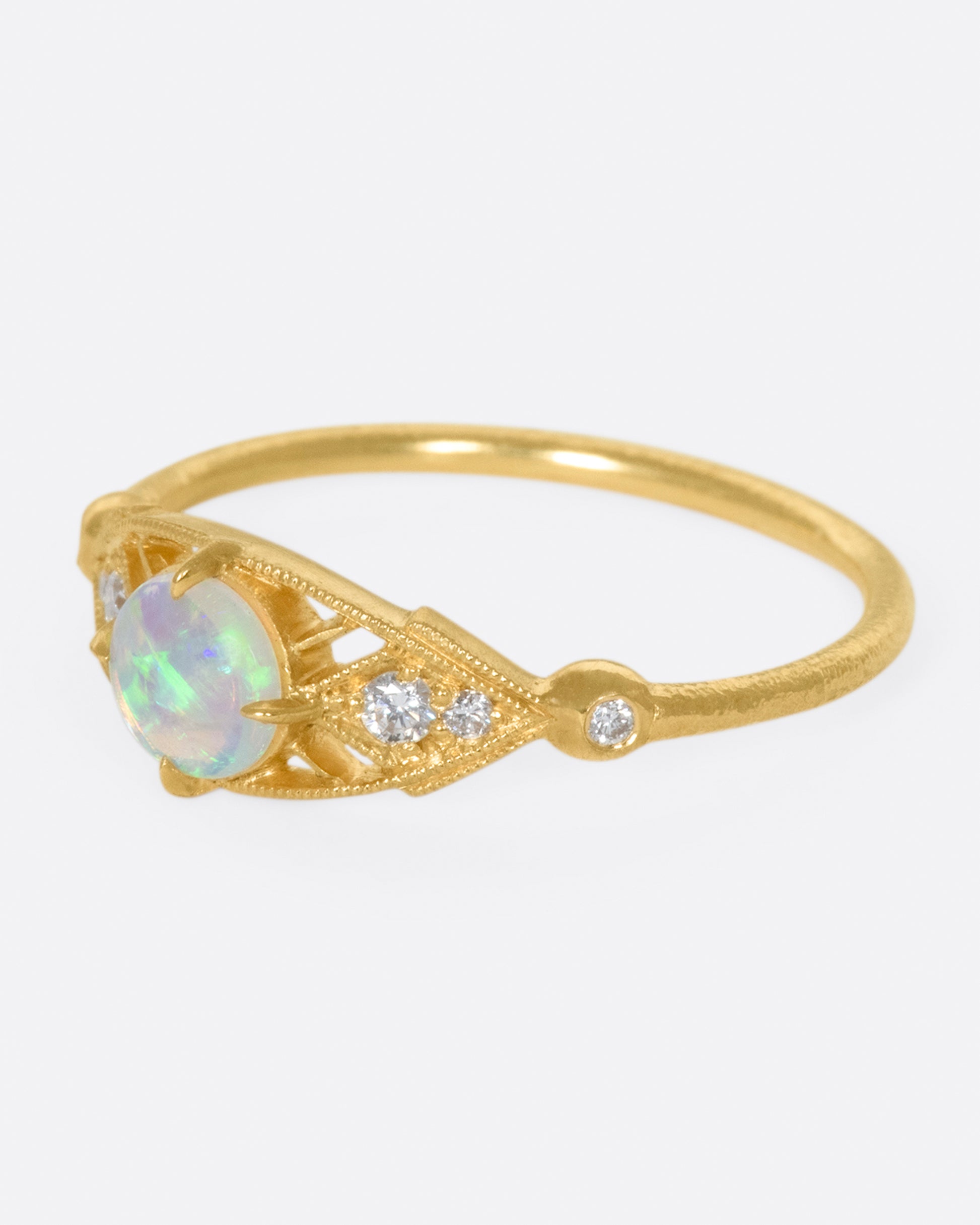 A glowy opal flanked with tiny, sparkly, diamonds, and set on a delicate band 14k gold band