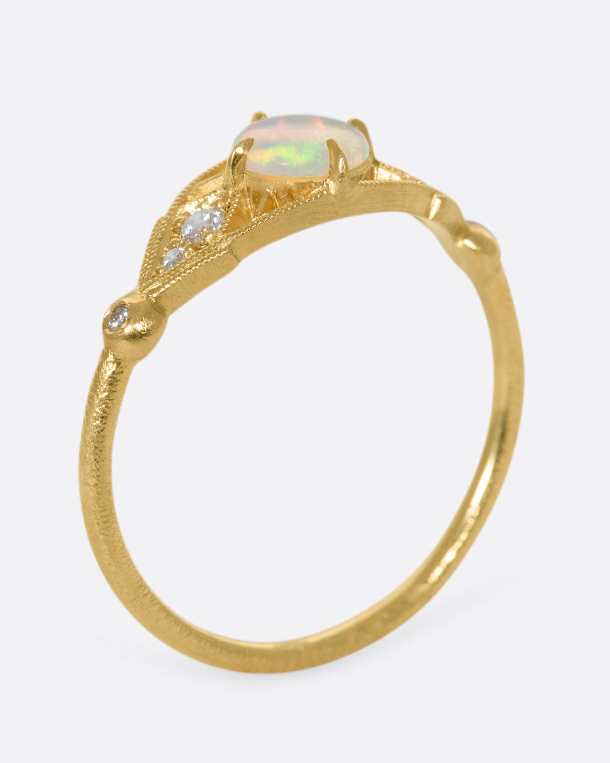 A glowy opal flanked with tiny, sparkly, diamonds, and set on a delicate band 14k gold band