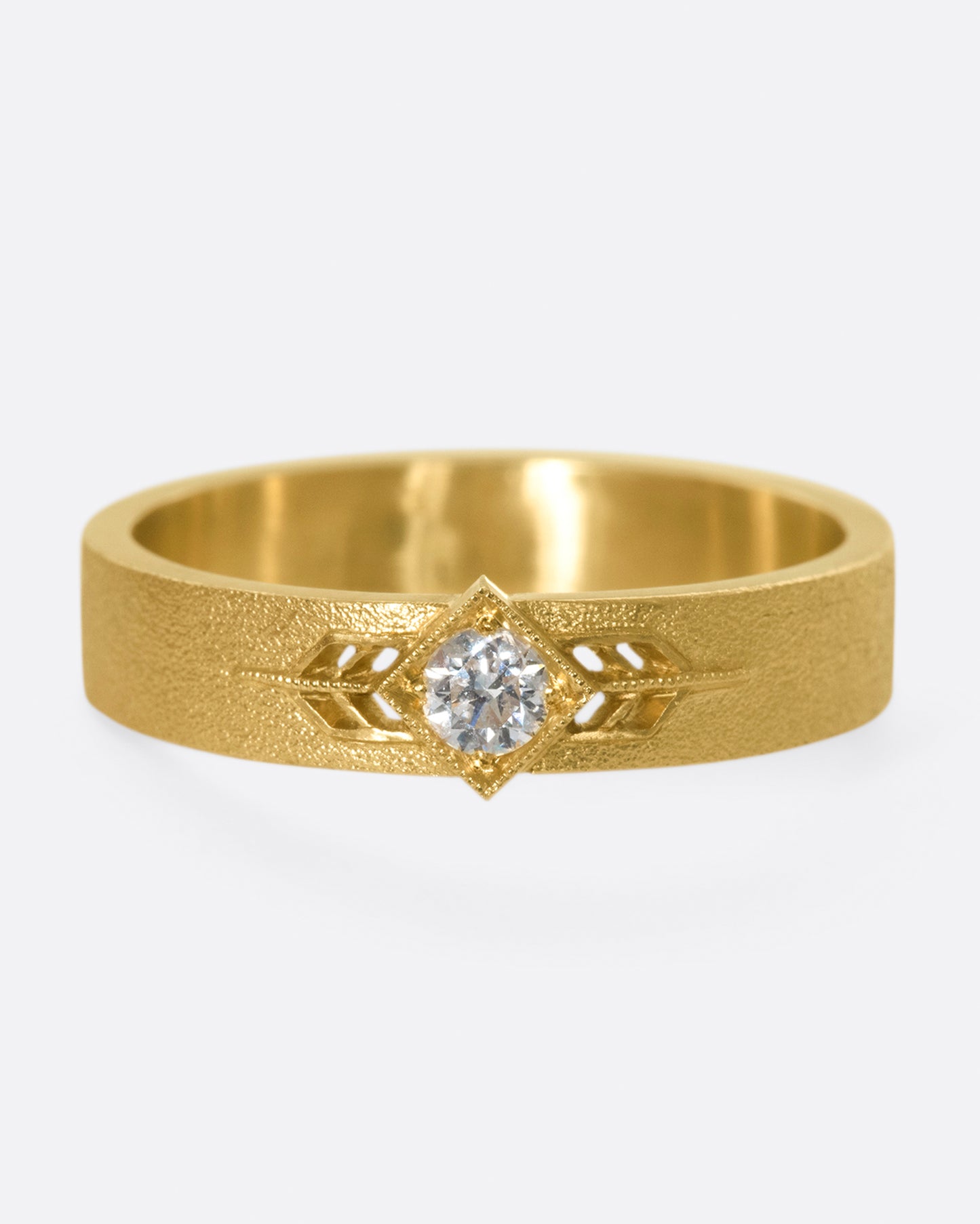 This 14k gold band has a stipple textured finish and an extremely sparkly, high-quality diamond popping in the center