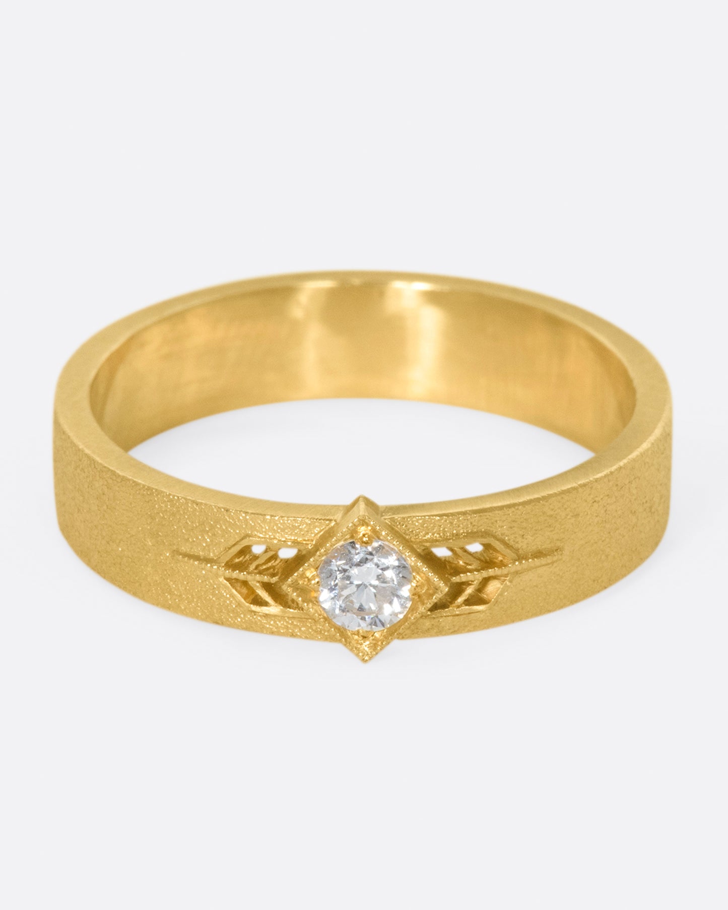 This 14k gold band has a stipple textured finish and an extremely sparkly, high-quality diamond popping in the center