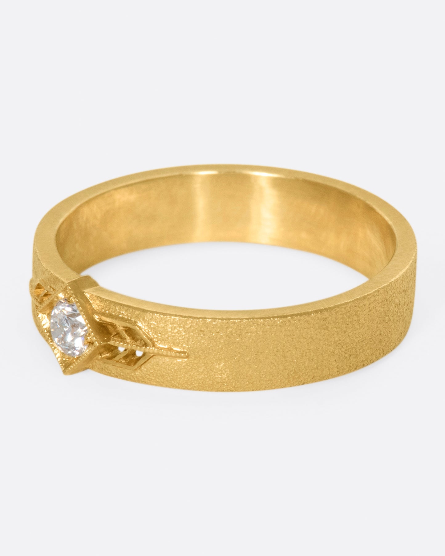 This 14k gold band has a stipple textured finish and an extremely sparkly, high-quality diamond popping in the center