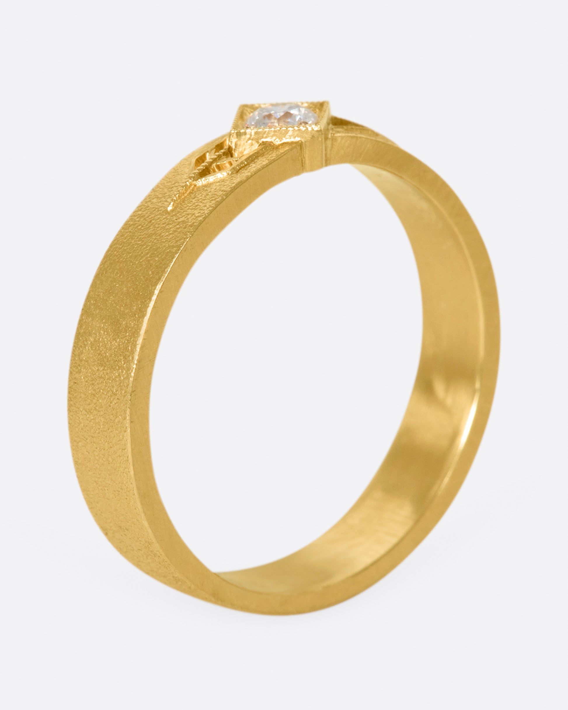 This 14k gold band has a stipple textured finish and an extremely sparkly, high-quality diamond popping in the center