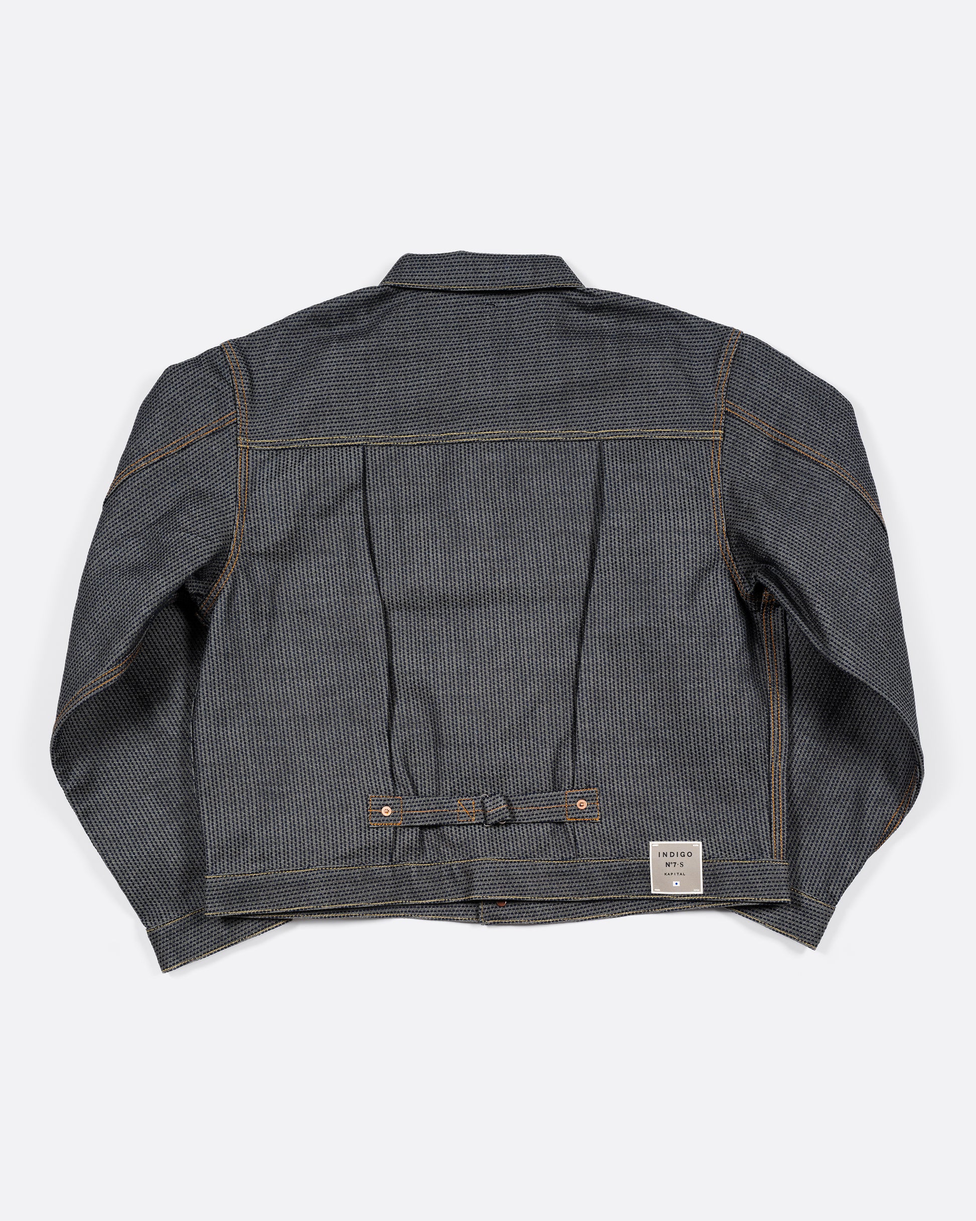 A dark blue textured button down denim jacket with a single pocket. View from the back showing the buckle detail.