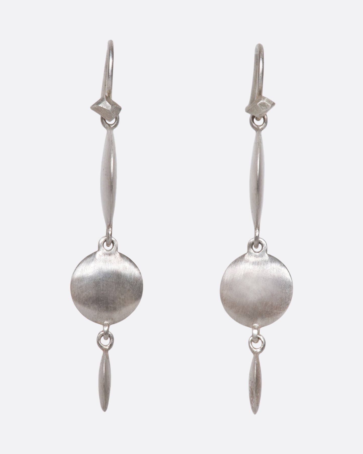 A pair of sterling silver triple drop dangles that juxtapose smooth, flat circular and oval faces against razor-thin edges