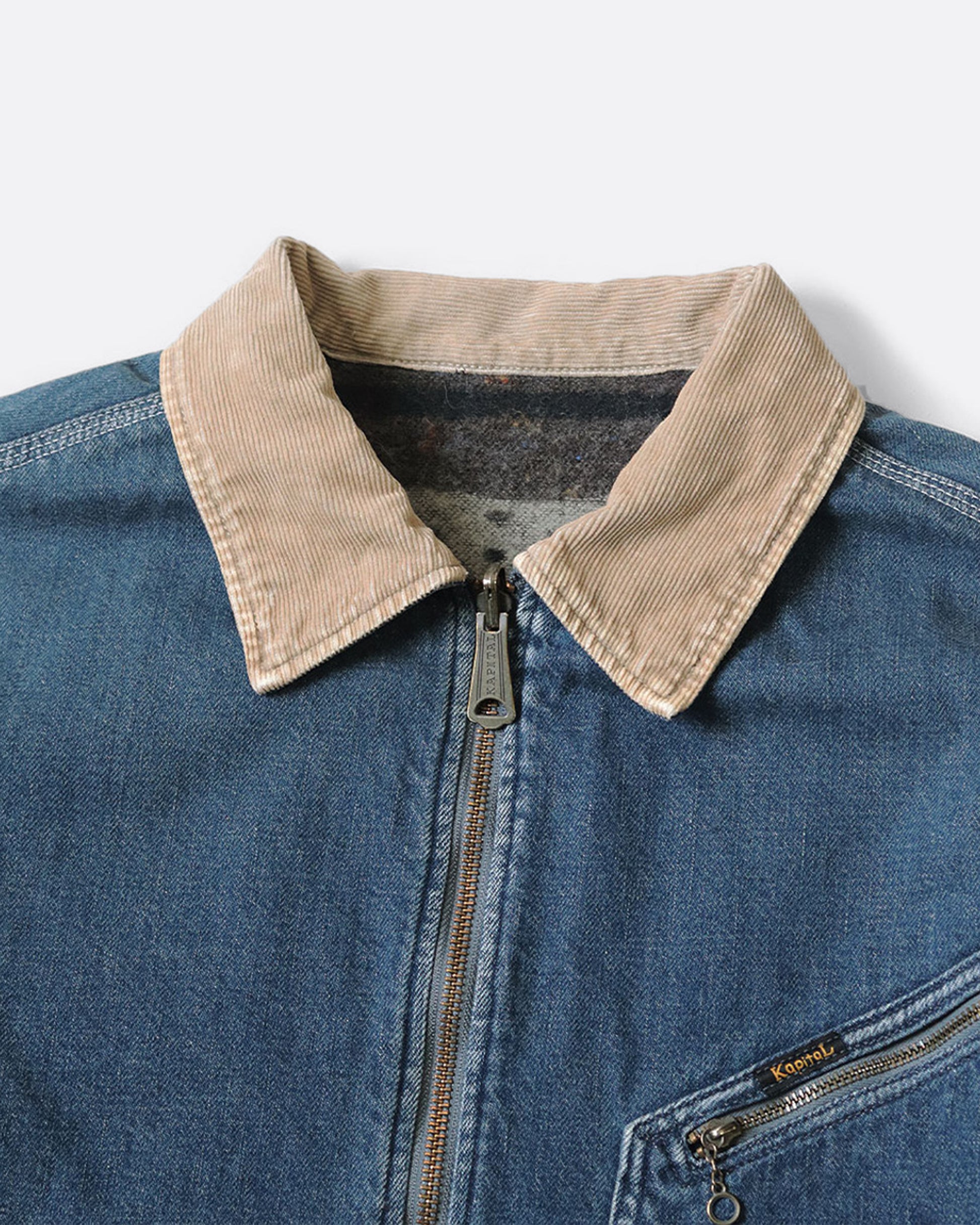A close up of a blue denim work jacket with a beige collar, lined in wool with a skeleton print. 