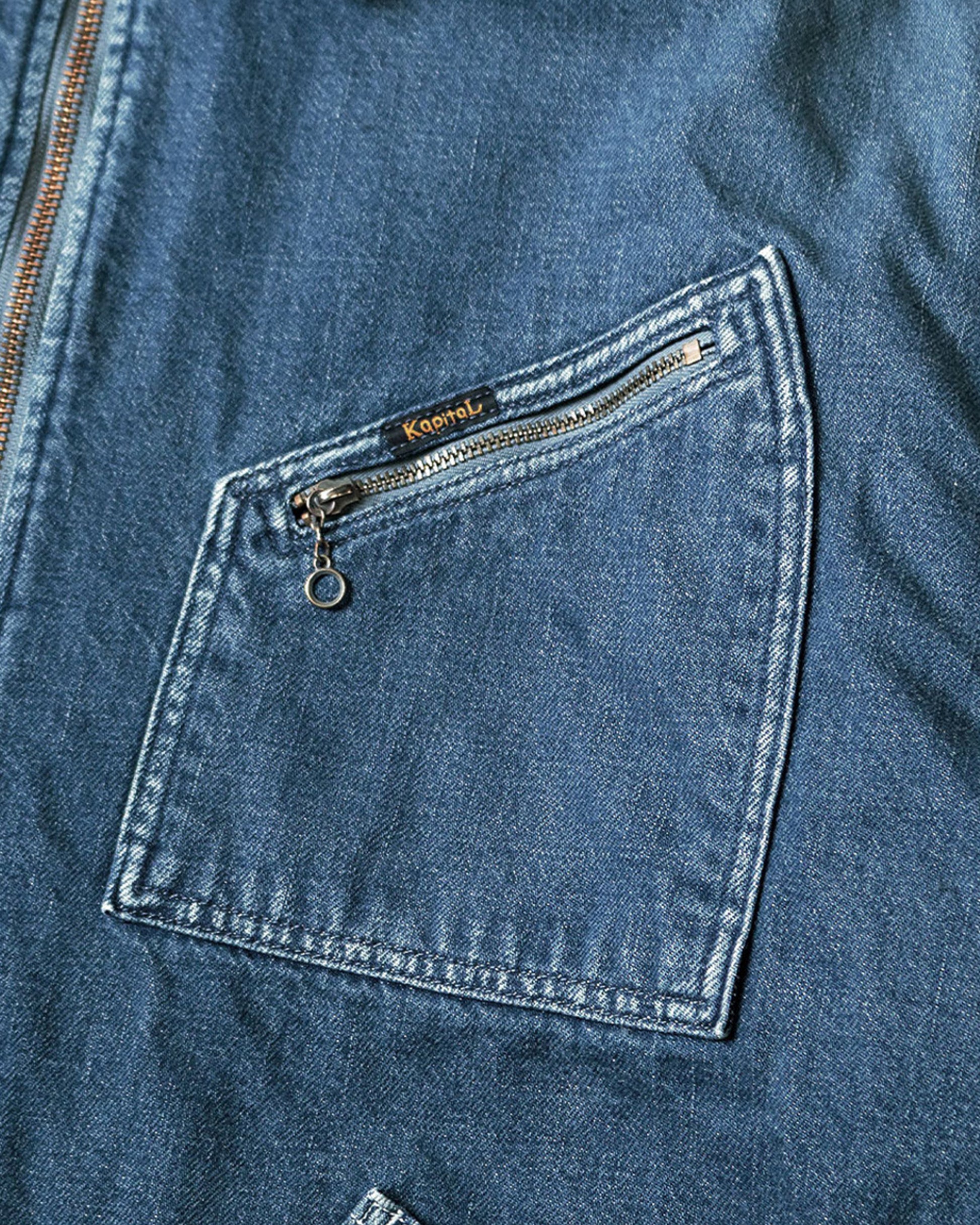 A close-up of the zip pocket on a blue denim jacket.