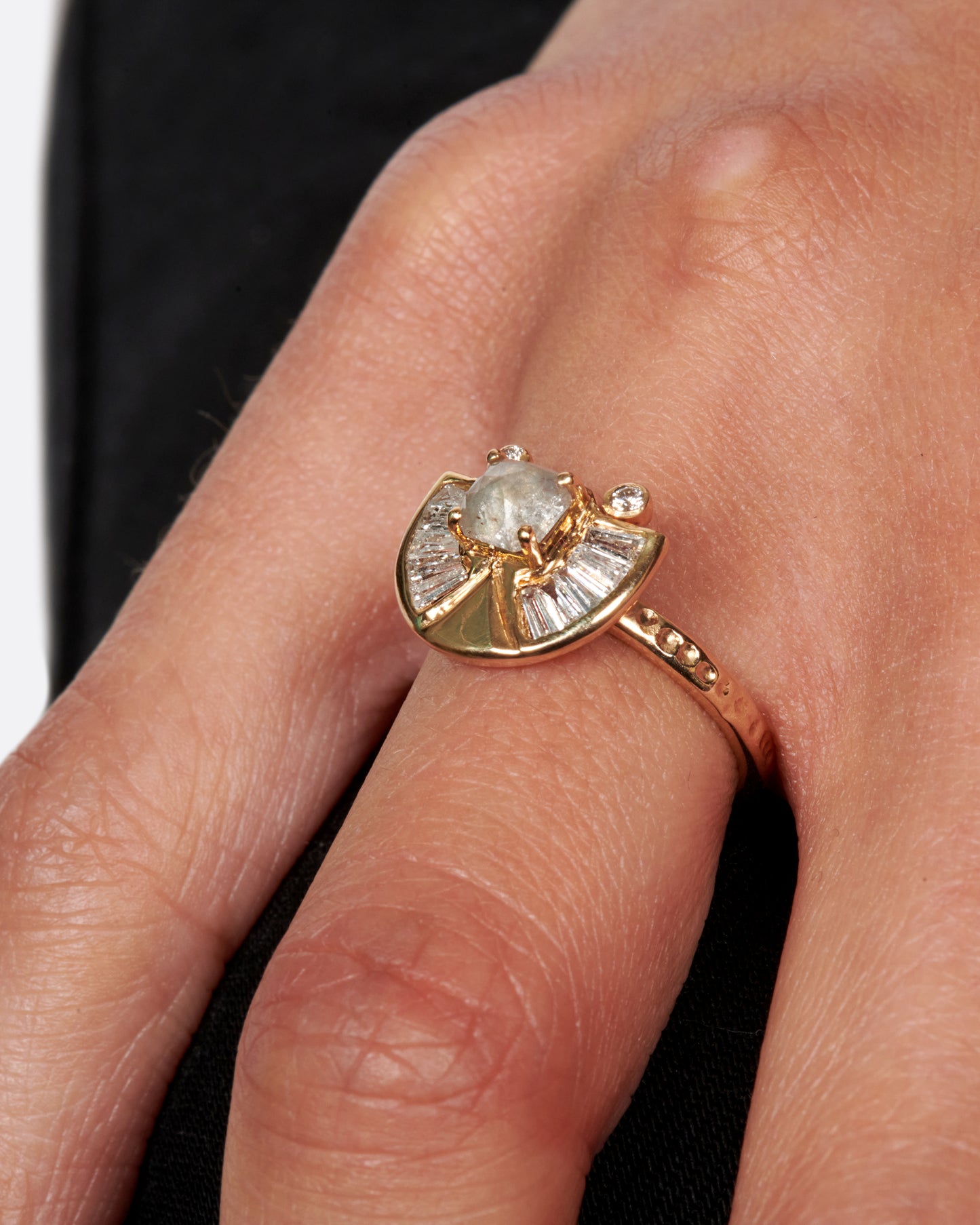 A textured gold ring with a rose cut salt & pepper diamond at its center surrounded by round and baguette diamond accents.