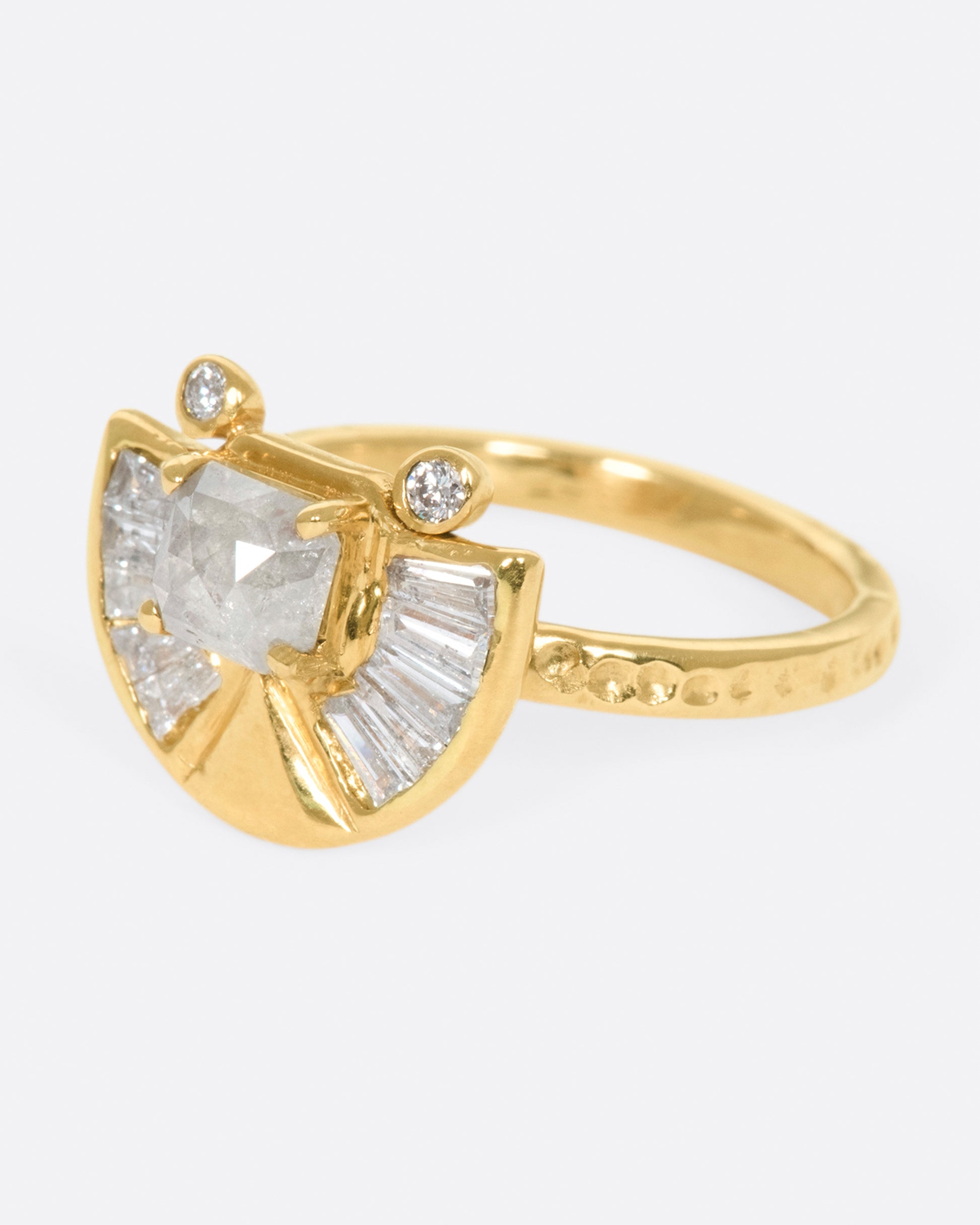 A textured gold ring with a rose cut salt & pepper diamond at its center surrounded by round and baguette diamond accents.