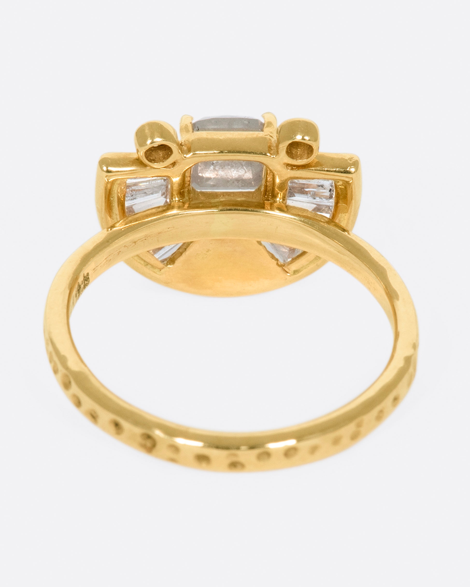 A textured gold ring with a rose cut salt & pepper diamond at its center surrounded by round and baguette diamond accents.