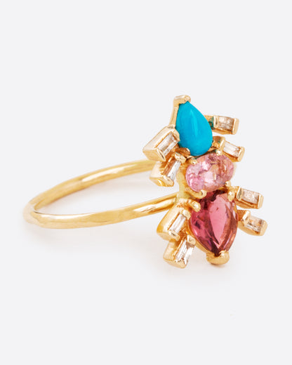 A yellow gold ring with pink tourmalines, turquoise, and baguette diamonds in the shape of an ant. Shown from the side.