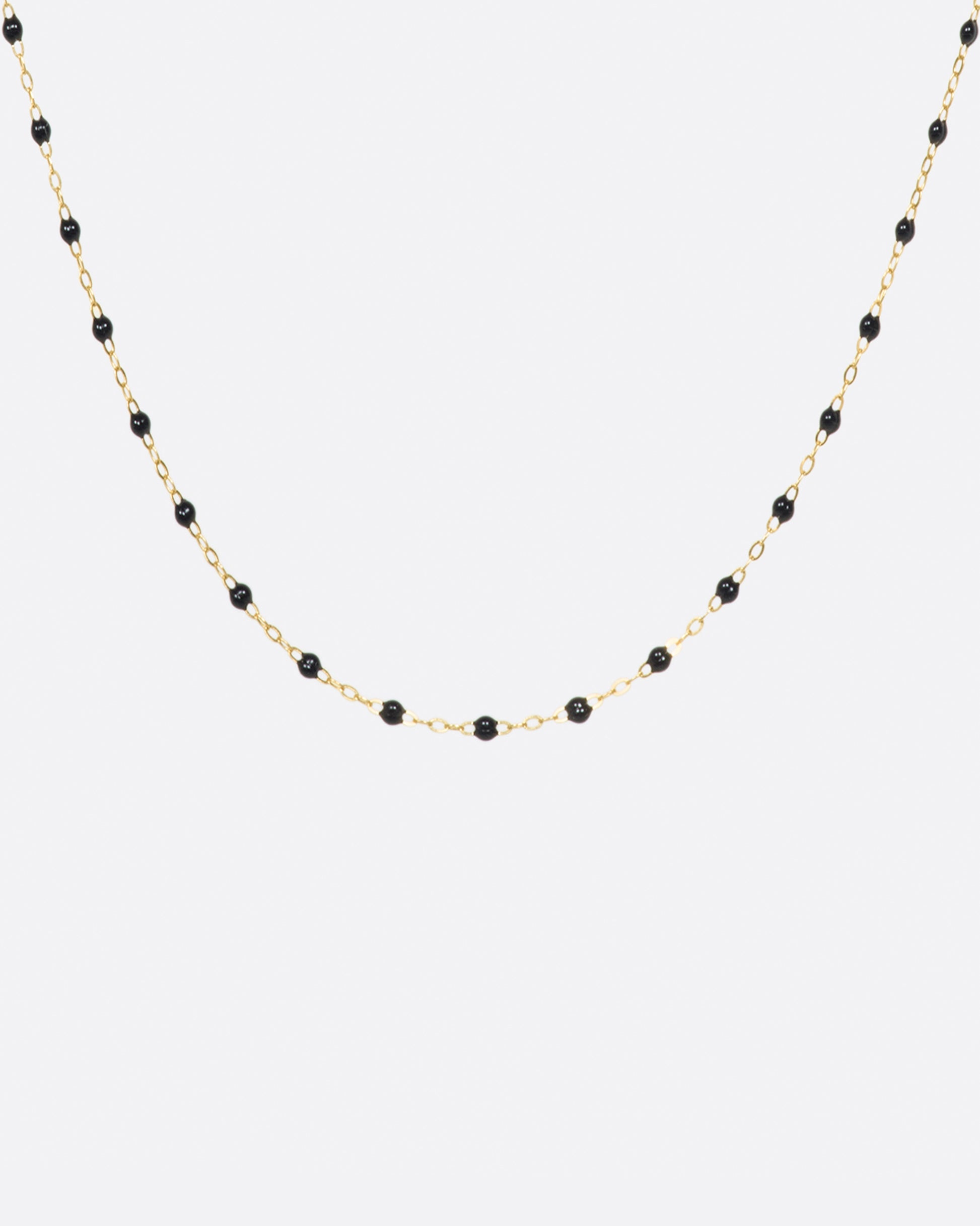 A thin yellow gold chain necklace with resin beads. Each necklace is hand dipped in melted resin to create the beaded effect. 