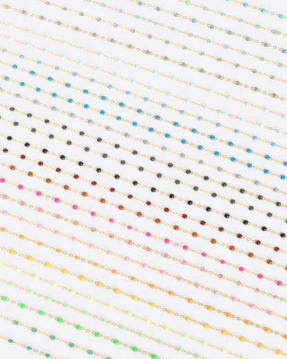 A bird's eye view of numerous yellow gold chains with different colors of resin beads.