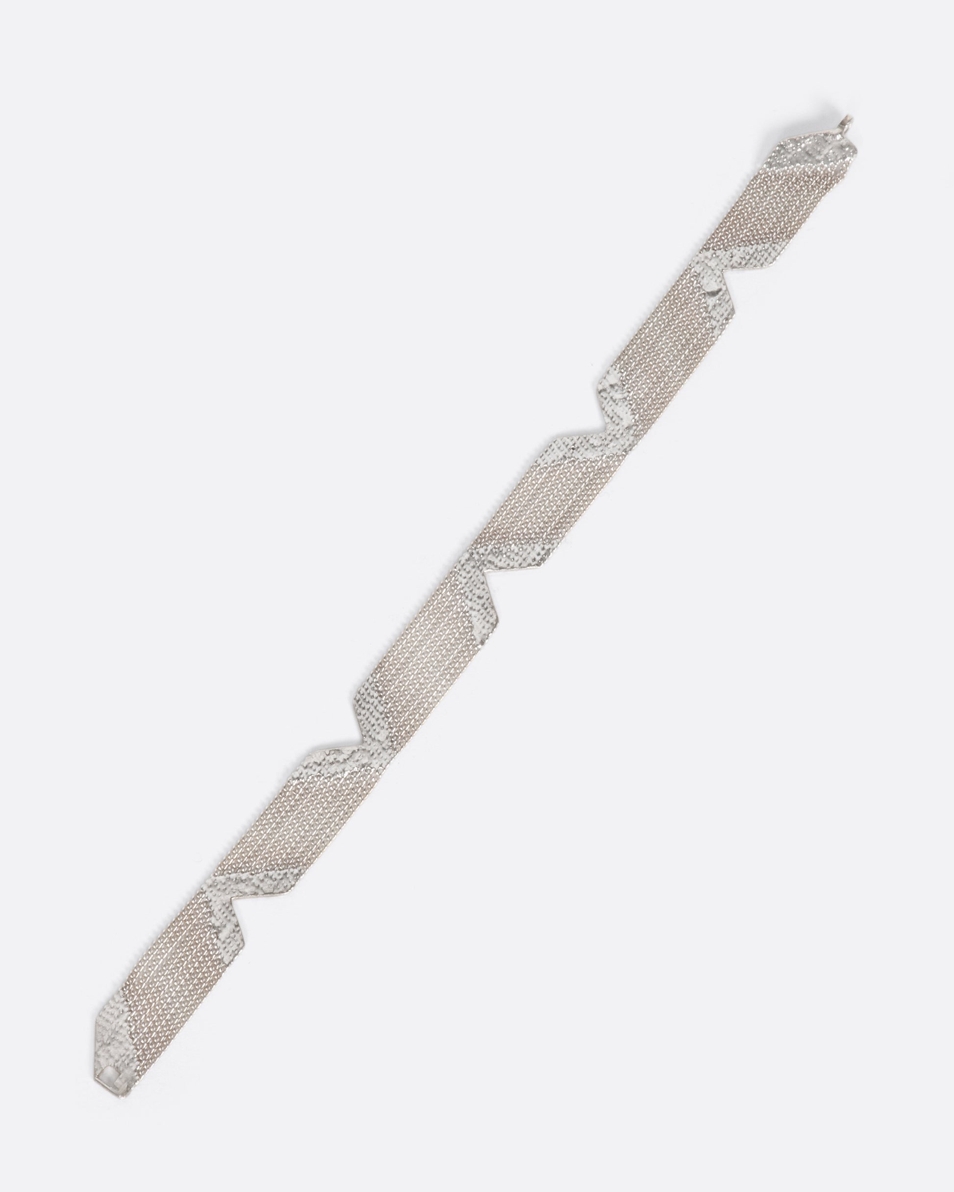 A sterling silver bracelet made out of multiple strands of chain, held together by solid sections of silver solder, with triangular cutouts along each side.