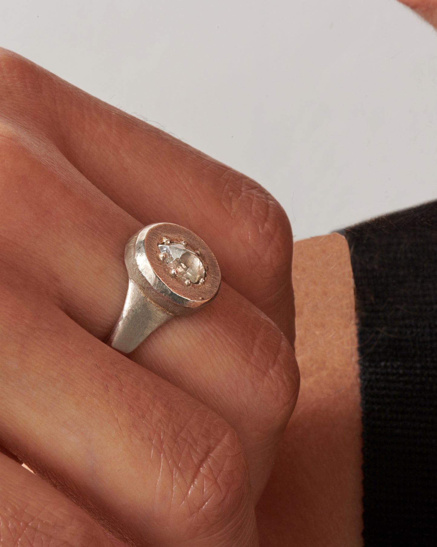 A sterling silver signet ring with a pear-shaped salt and pepper diamond secured with tiny prongs