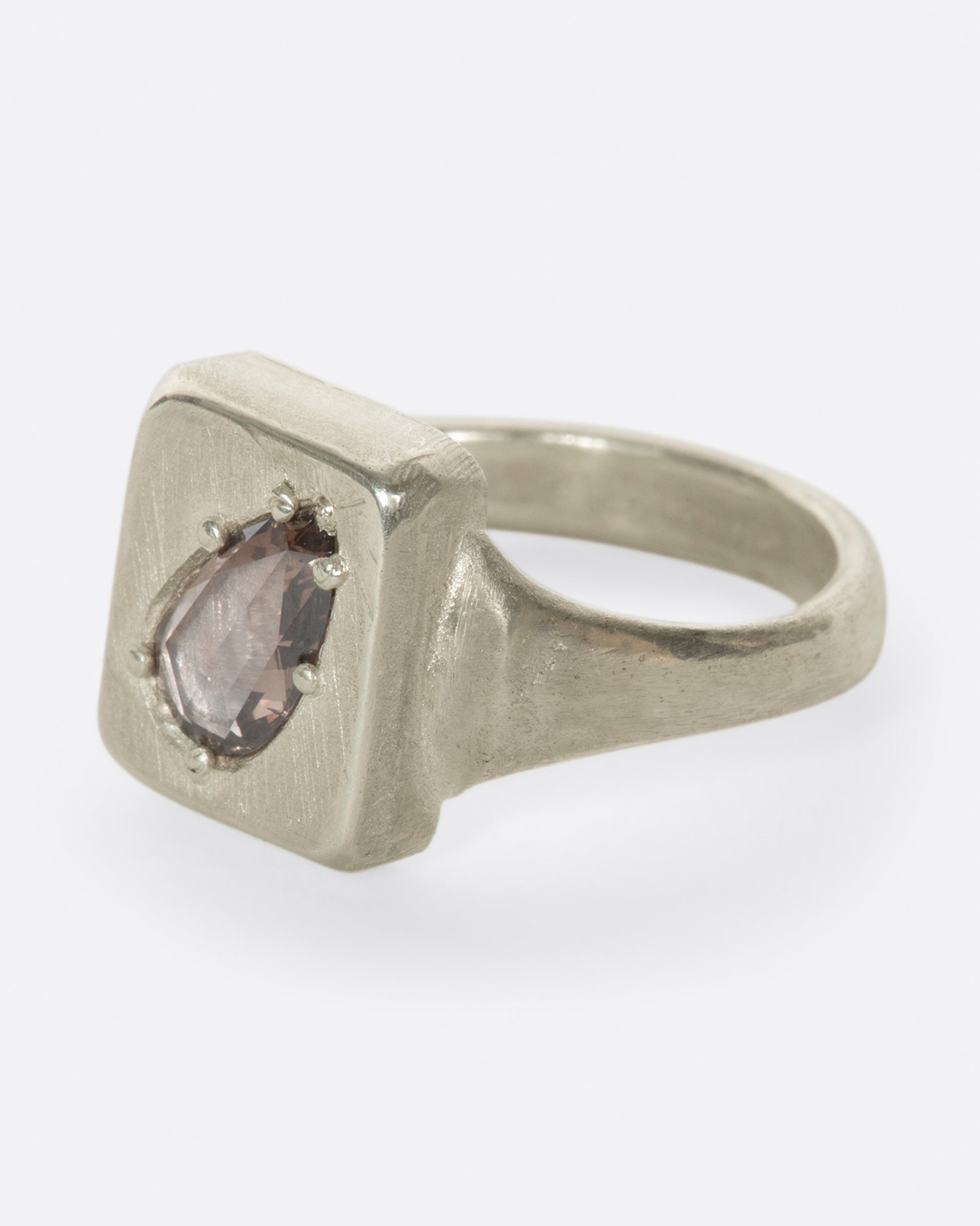 A handmade square signet ring with a cognac diamond sunken into it.