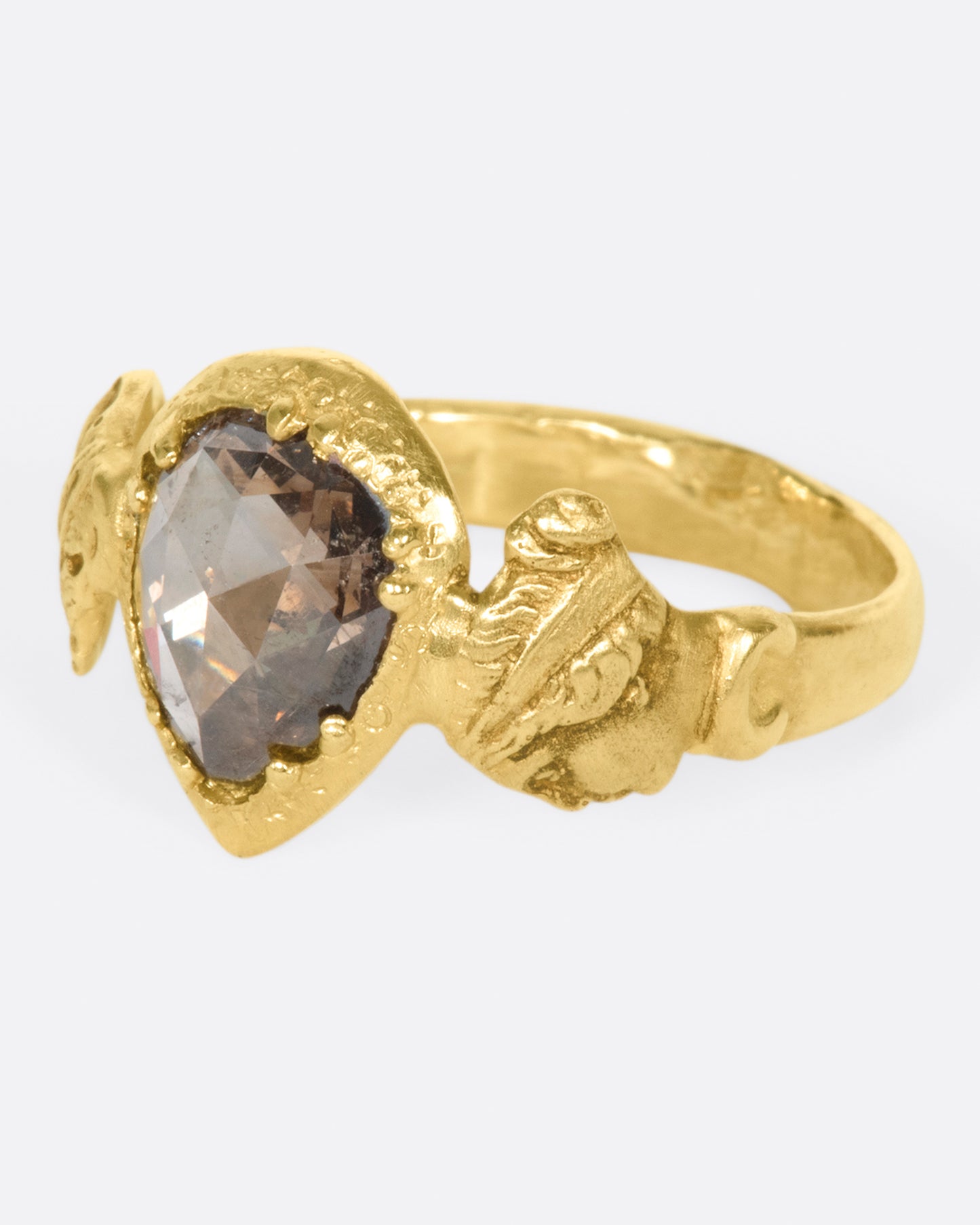 This moody pear-shaped cognac diamond, swirling with chocolaty hues, in an open-back setting that invites light to reflect intensely. The hand-carved bezel and band give a deeply storied feel as if this were dug up in the desert—treasure left behind by an ancient Roman civilization.