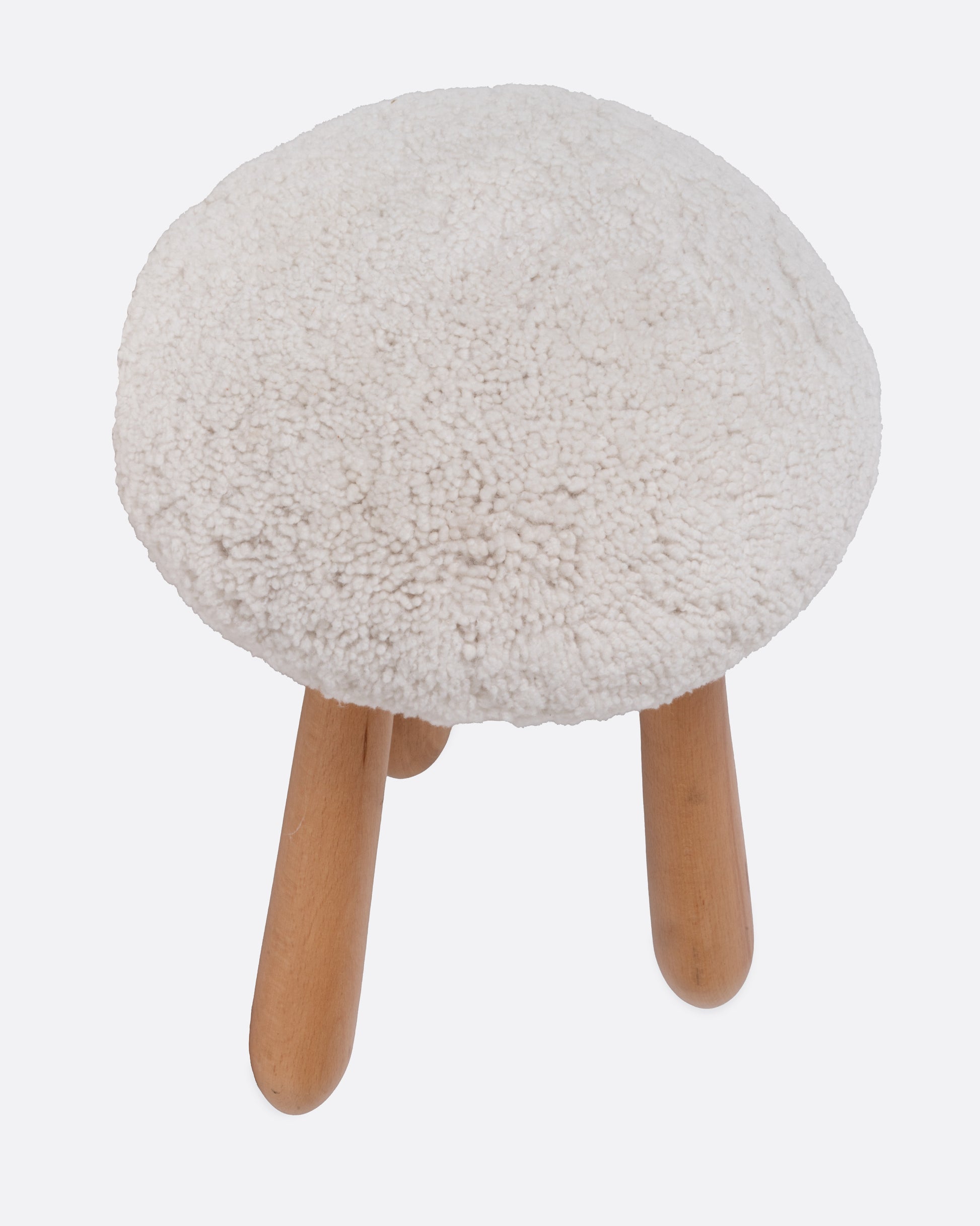A domed shearling stool with three wooden legs, shown from the top.