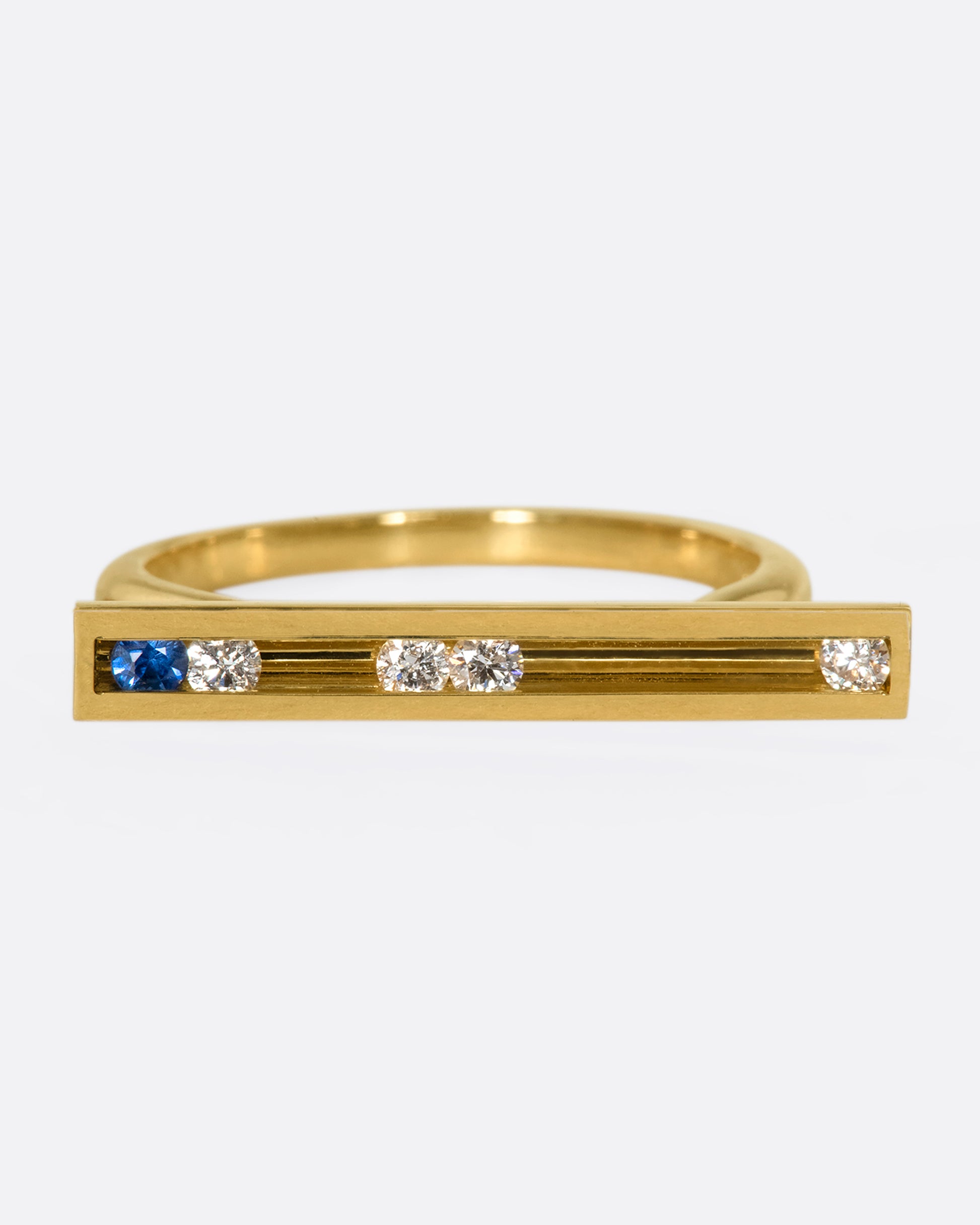 A flat-face ring with blue sapphires and diamonds that glide across an 18K gold bar.