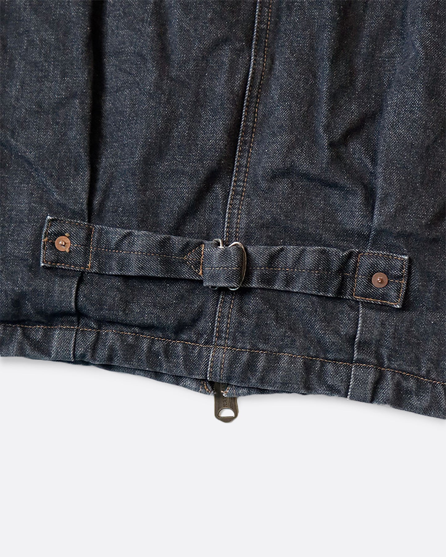 A dark blue denim bomber jacket with a corduroy collar and two front pockets. Close up view of the buckle a the back.