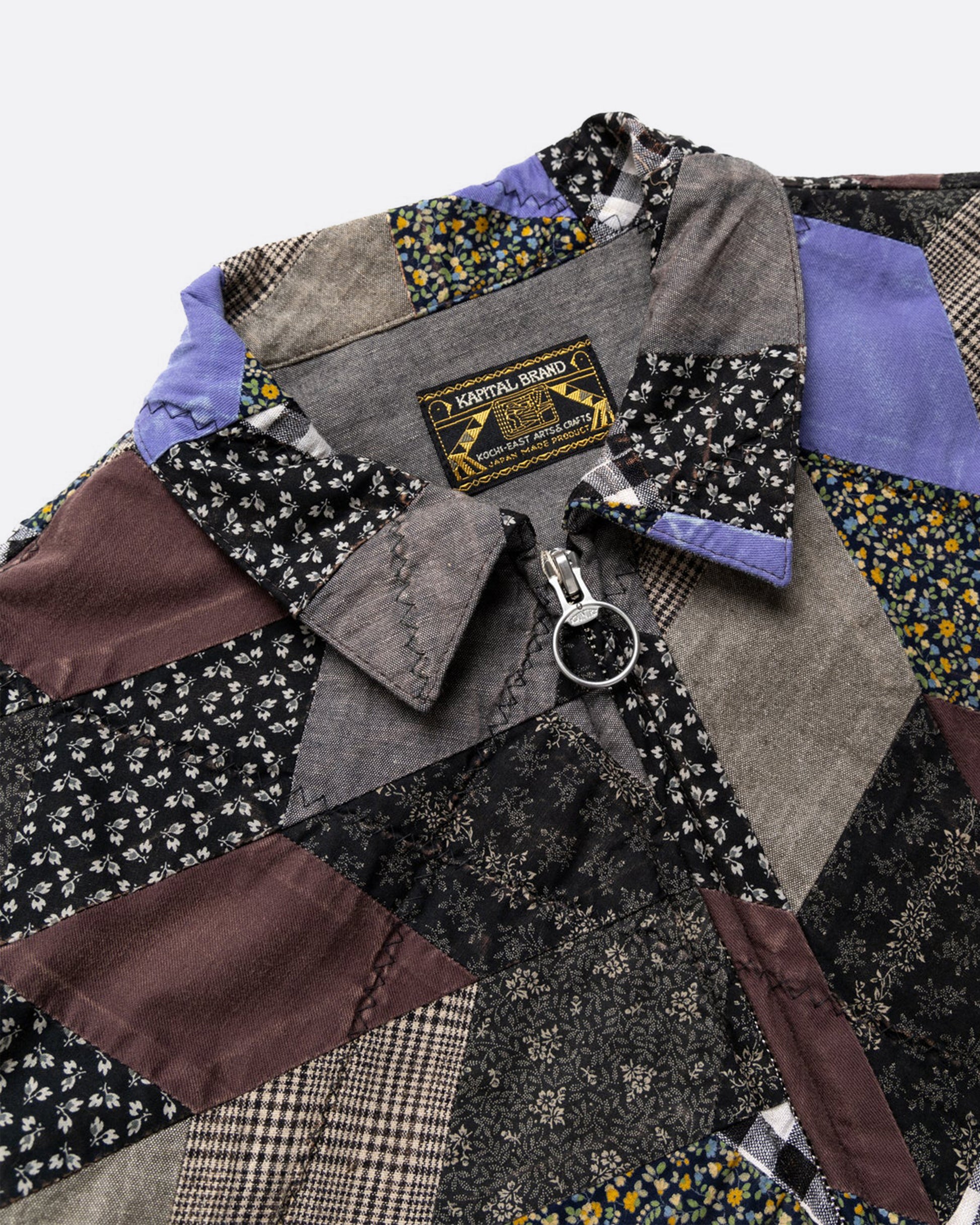 A cropped jacket with an arrow shaped patchwork and zip front. Shown close up from the front.