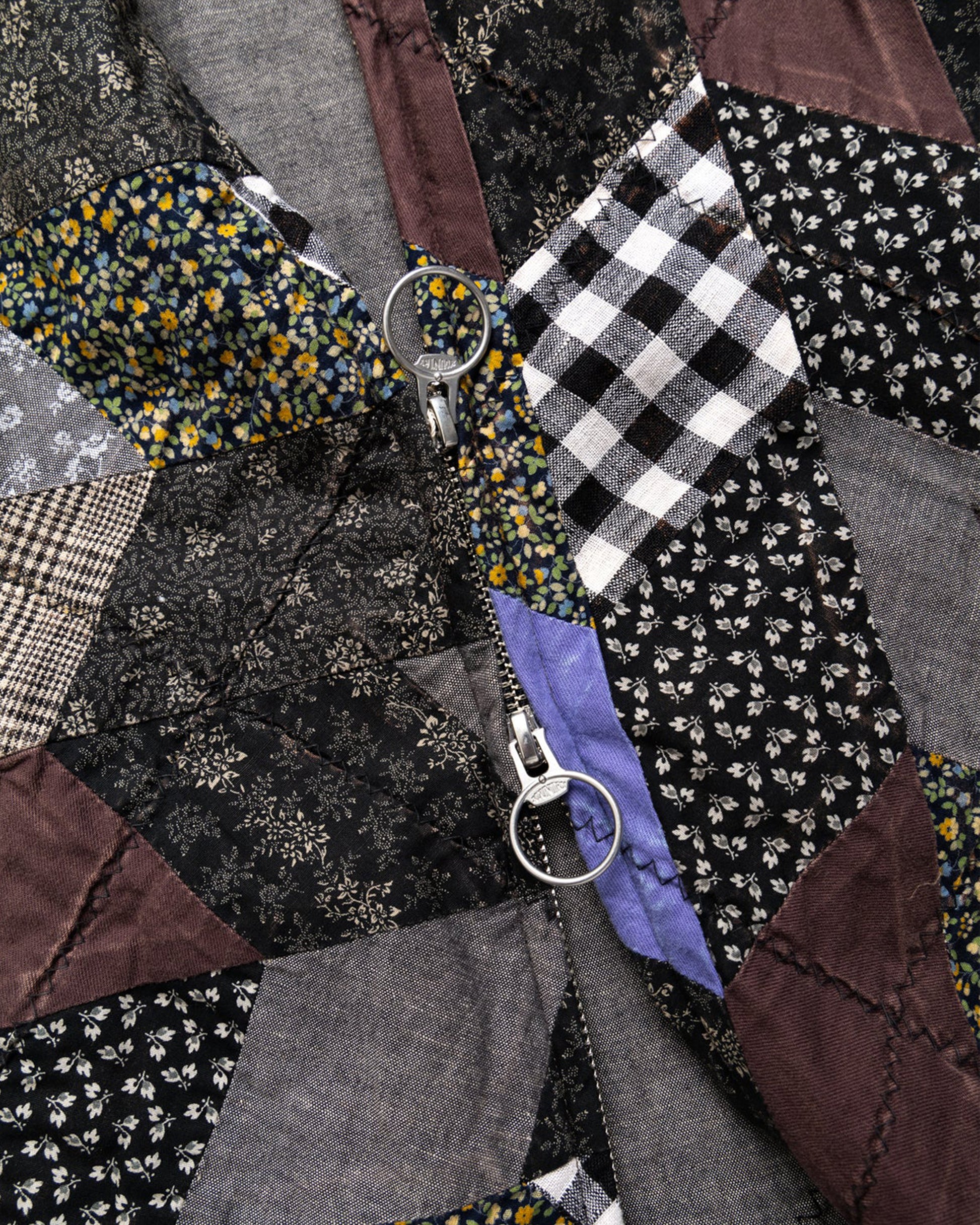A cropped jacket with an arrow shaped patchwork and zip front. Shown close up from the front.