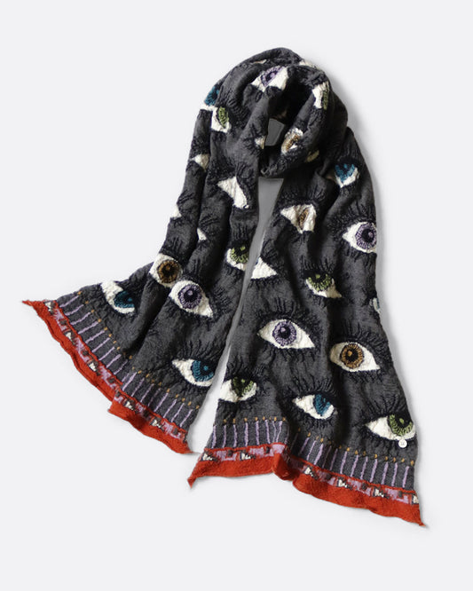A charcoal gray compressed wool scarf with an all- over eye pattern, shown wrapped with one loop in the middle.