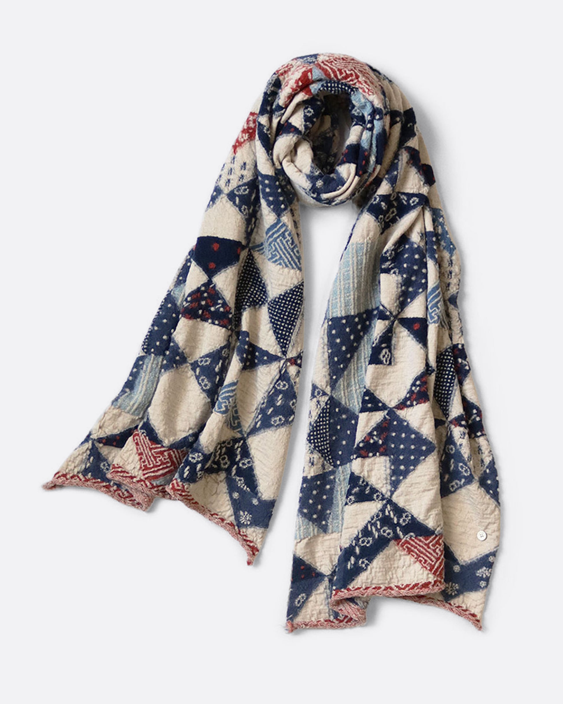A cream and blue compressed wool scarf with an all- over quilt pattern, shown wrapped with one loop.