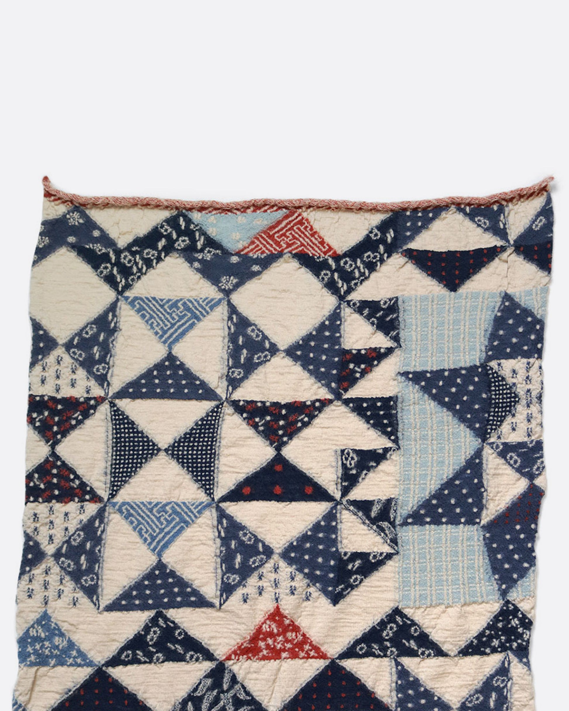 A cream and blue compressed wool scarf with an all- over quilt pattern, shown open lying flat.