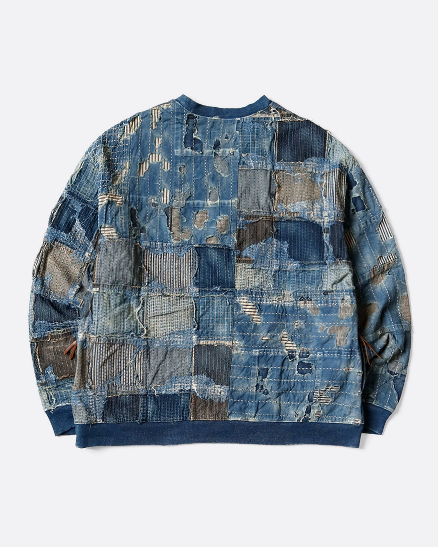A crewneck sweatshirt with an indigo dyed cotton front and a distressed Boro patchwork on the reverse. Shown from the back.